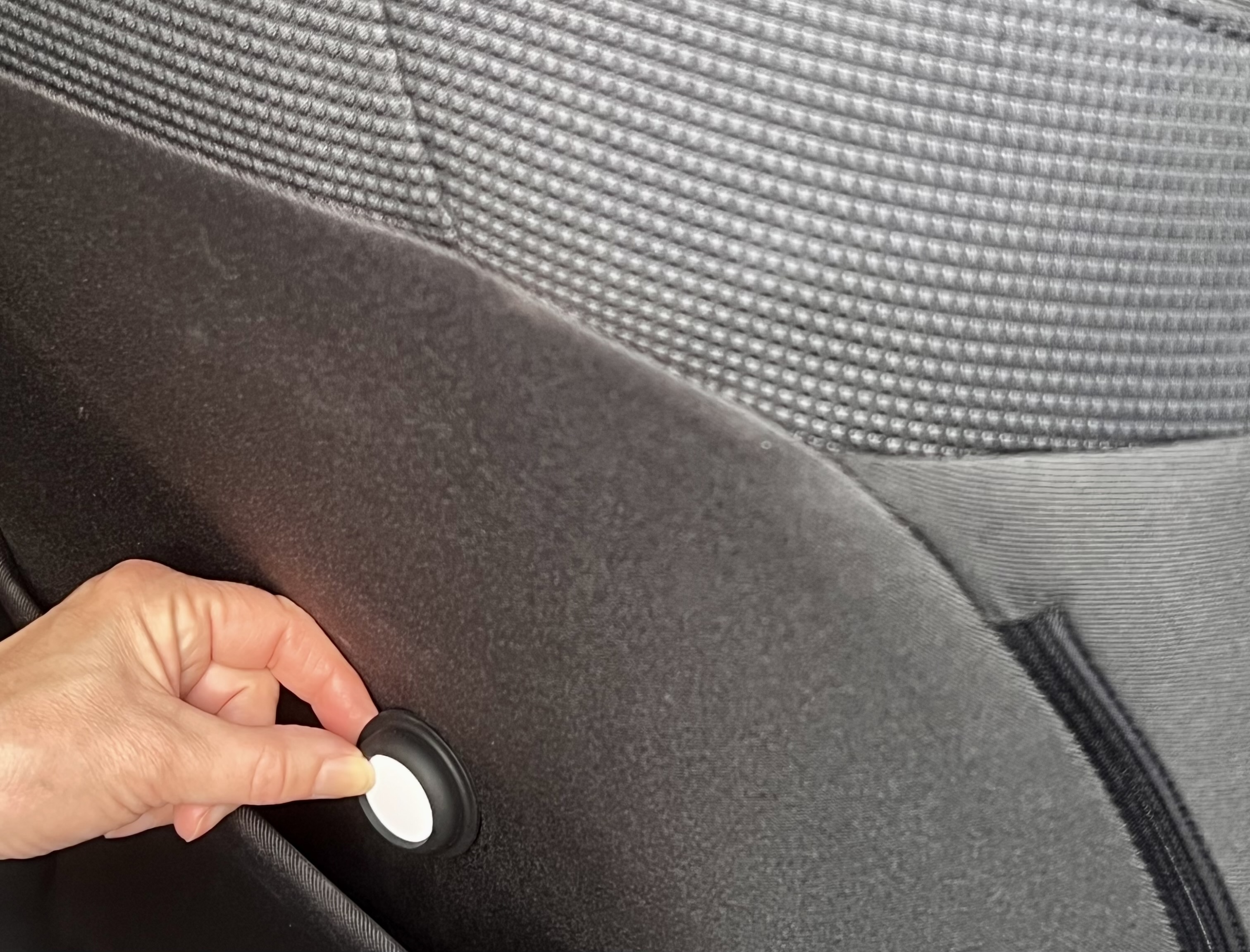 AirTag in an adhesive holder attached to the inside of a car seat.