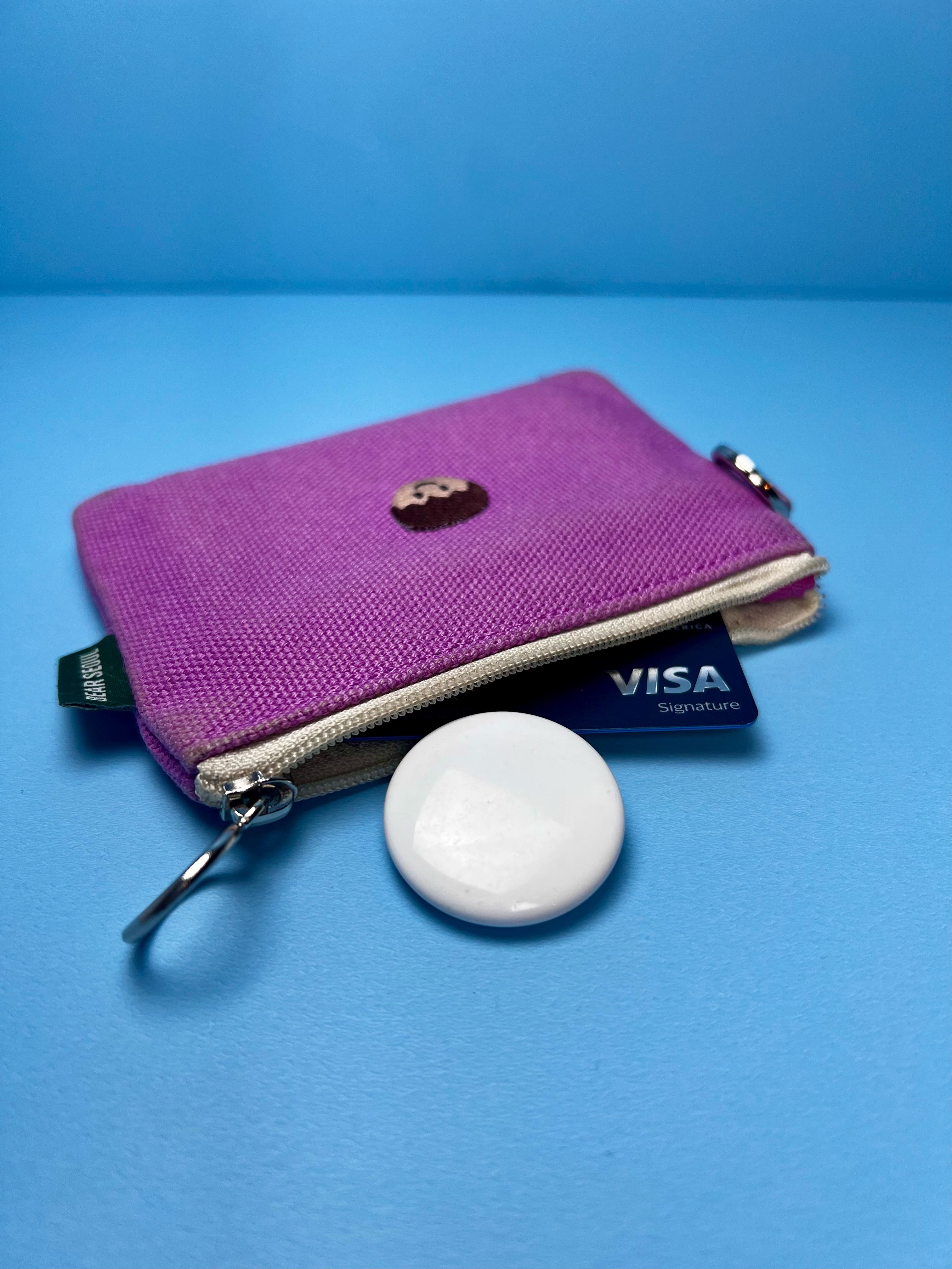 White AirTag beside a small wallet and credit card.
