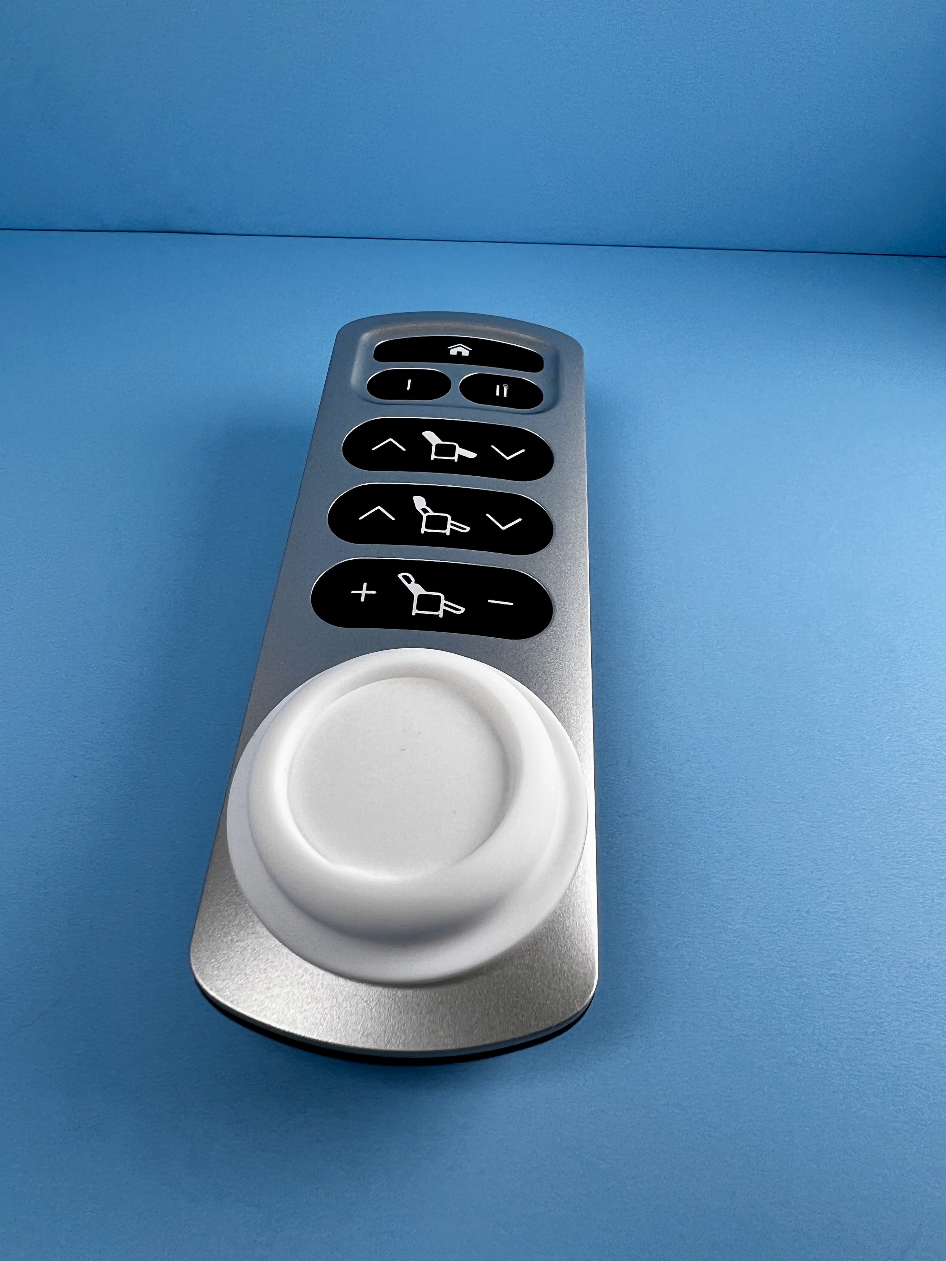 White AirTag attached to a remote control.
