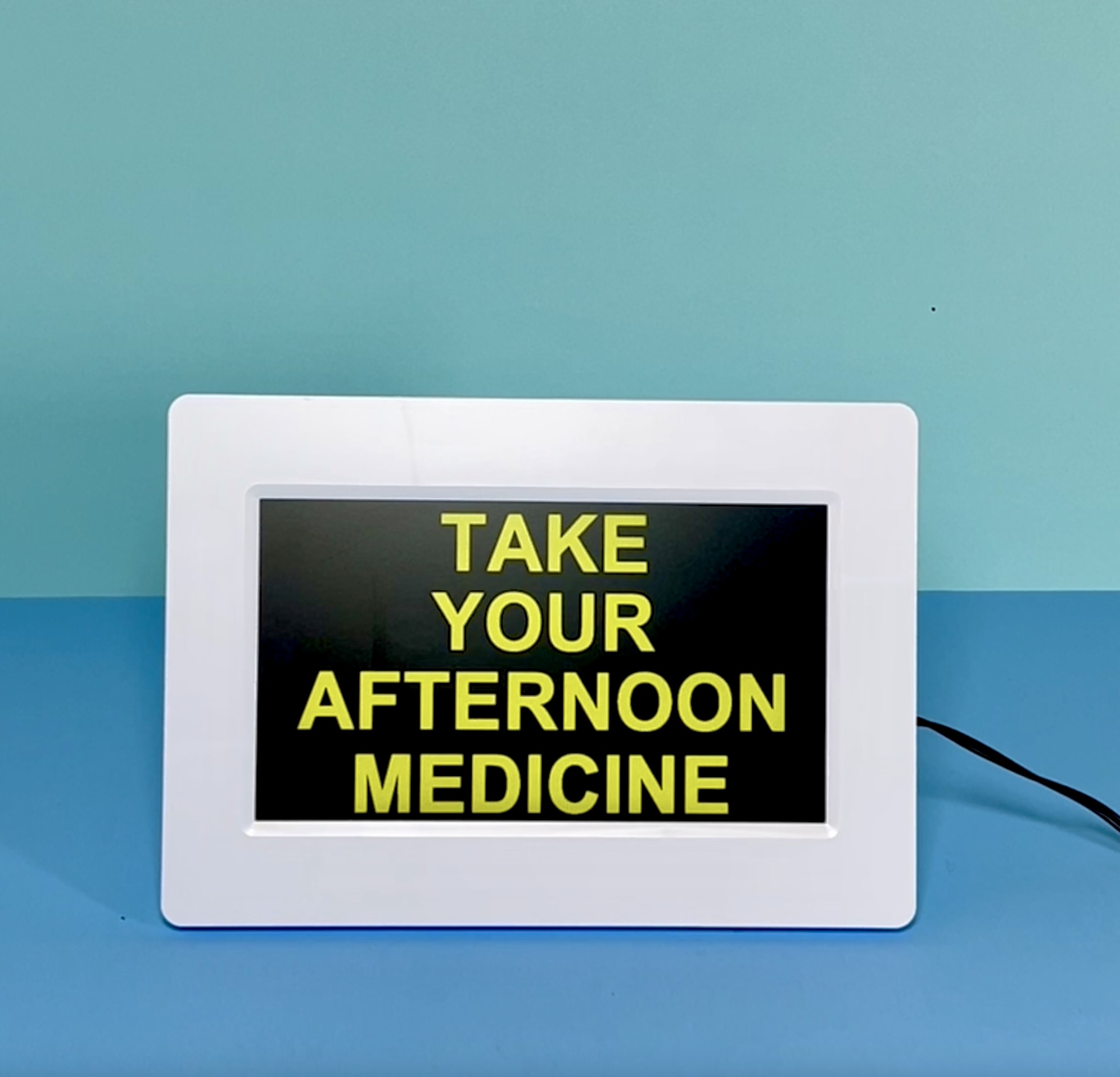 Digital clock displaying a reminder that says, “Take Your Afternoon Medicine.”