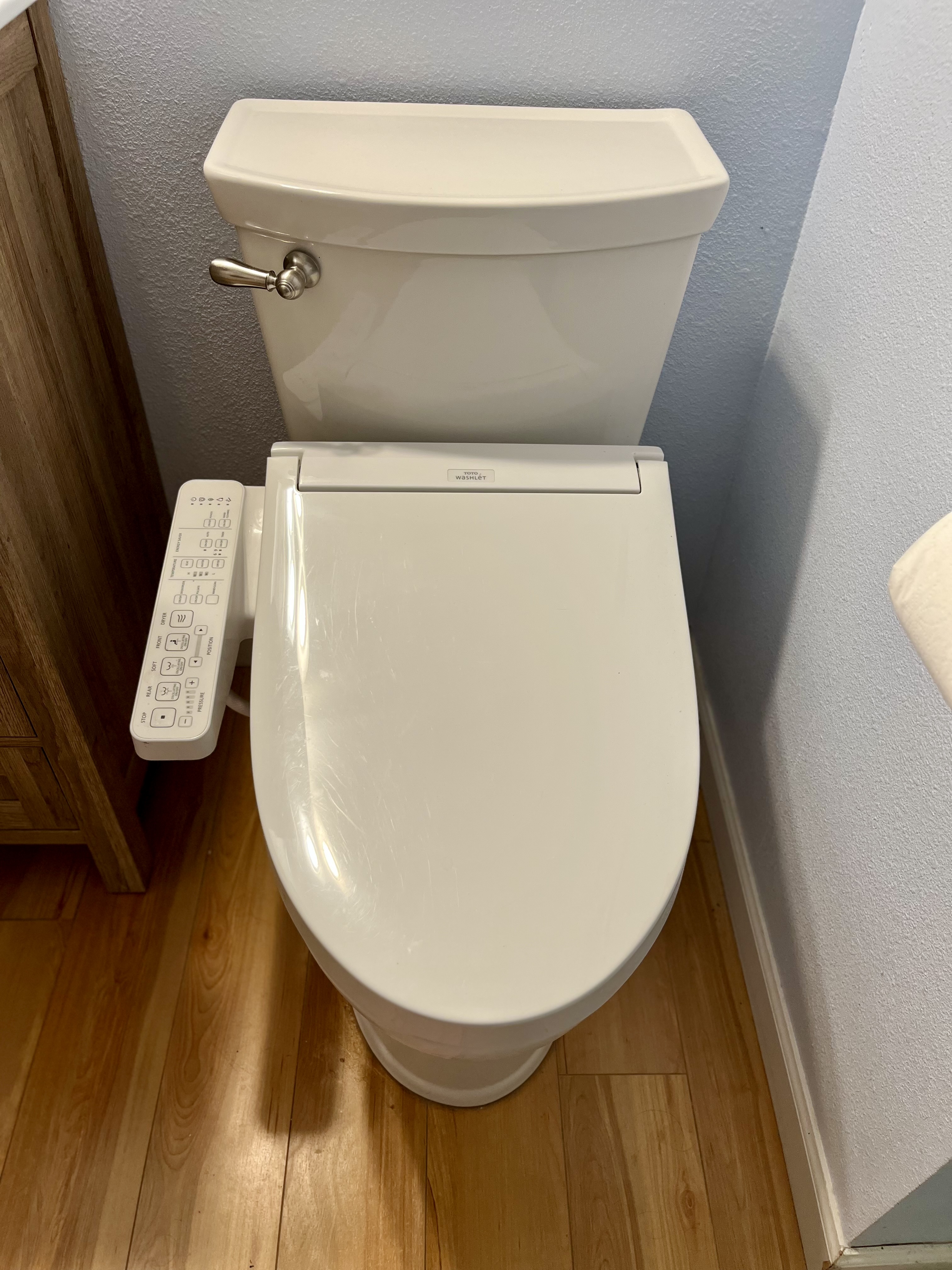 White toilet with an electronic bidet seat and side control panel.