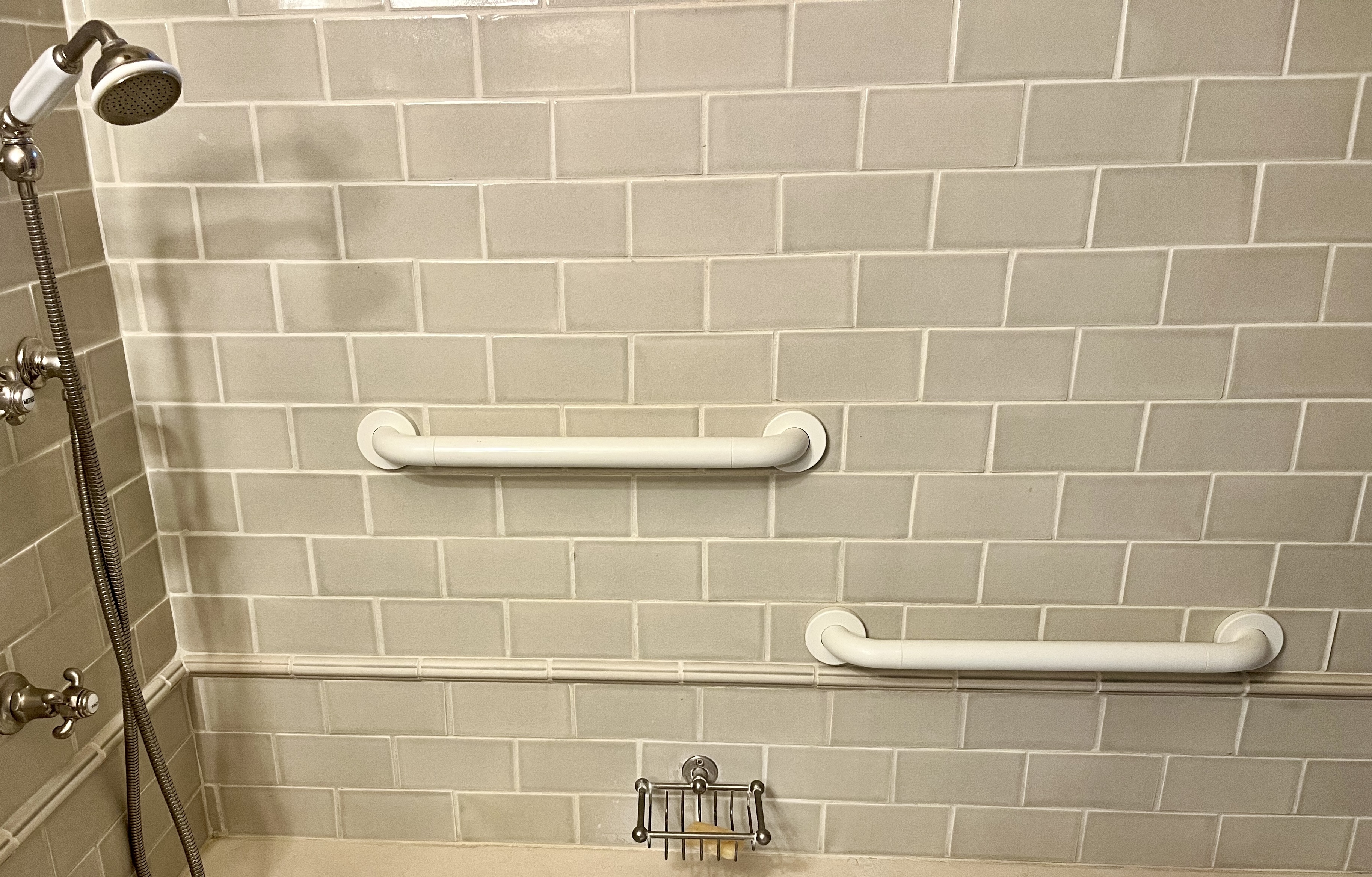 Two white grab bars mounted in a shower.