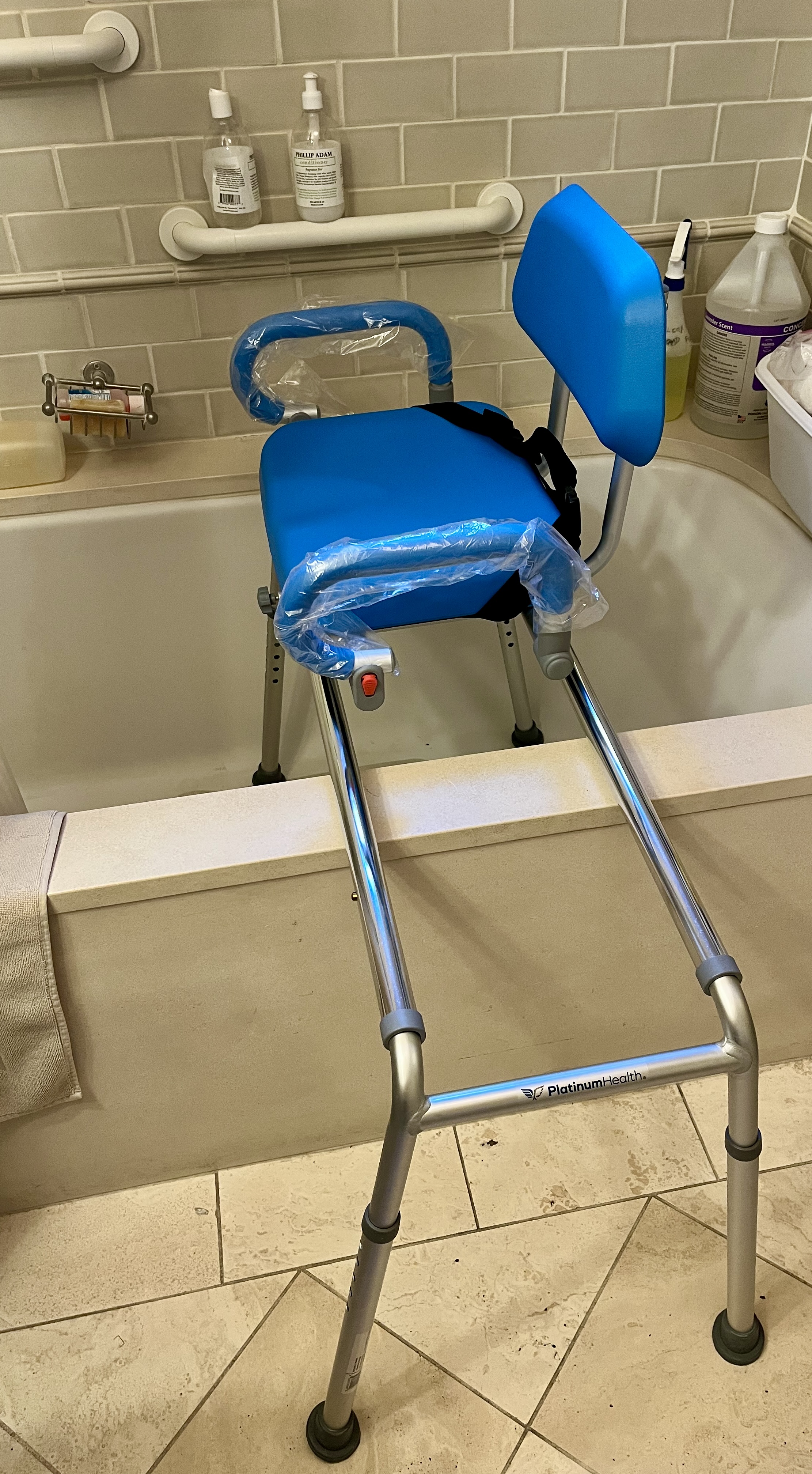 Blue padded transfer bench positioned across a bathtub to help with safer seated entry and exit.
