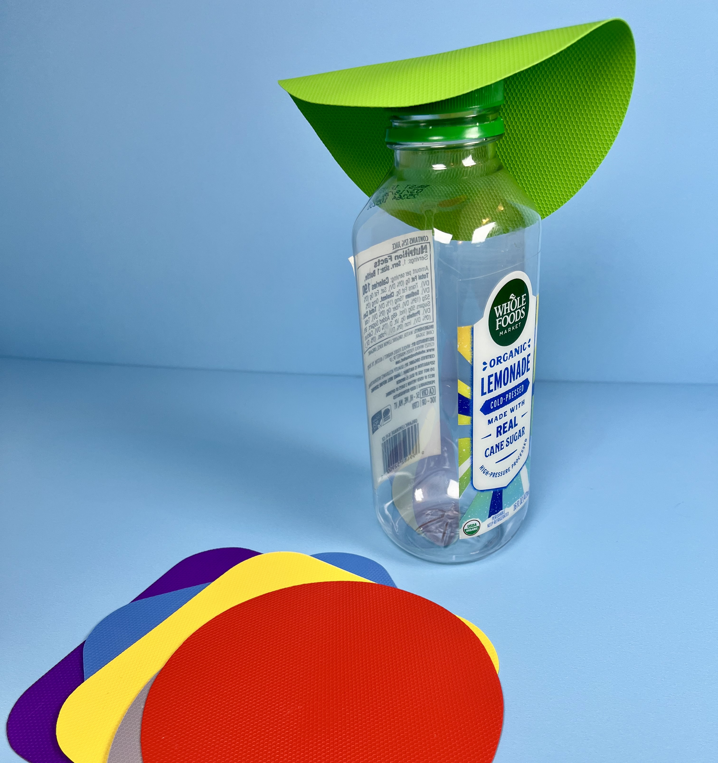 Silicone gripper wrapped around a bottle cap, with colorful grip pads nearby.