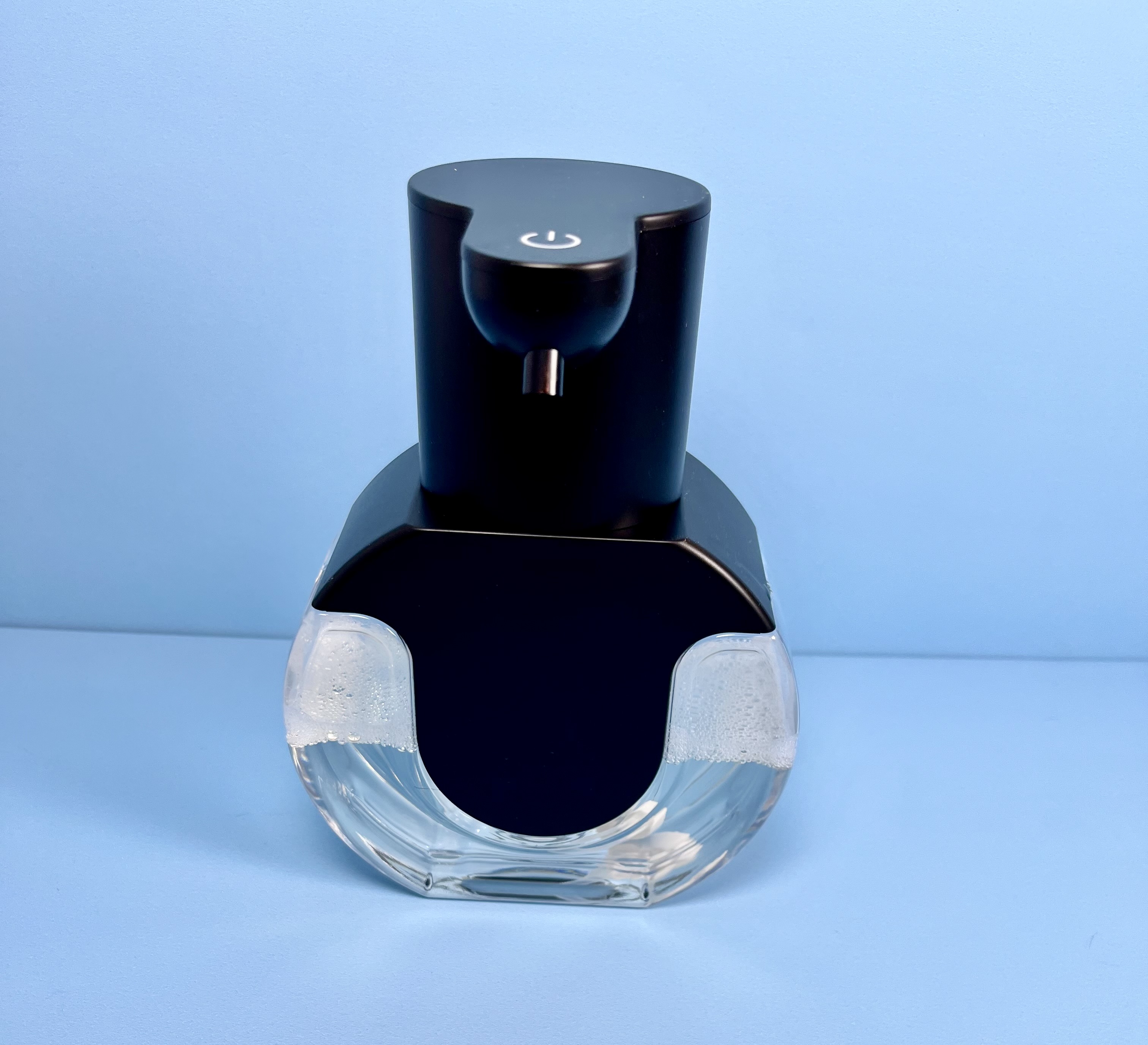 Automatic soap dispenser against a blue background.
