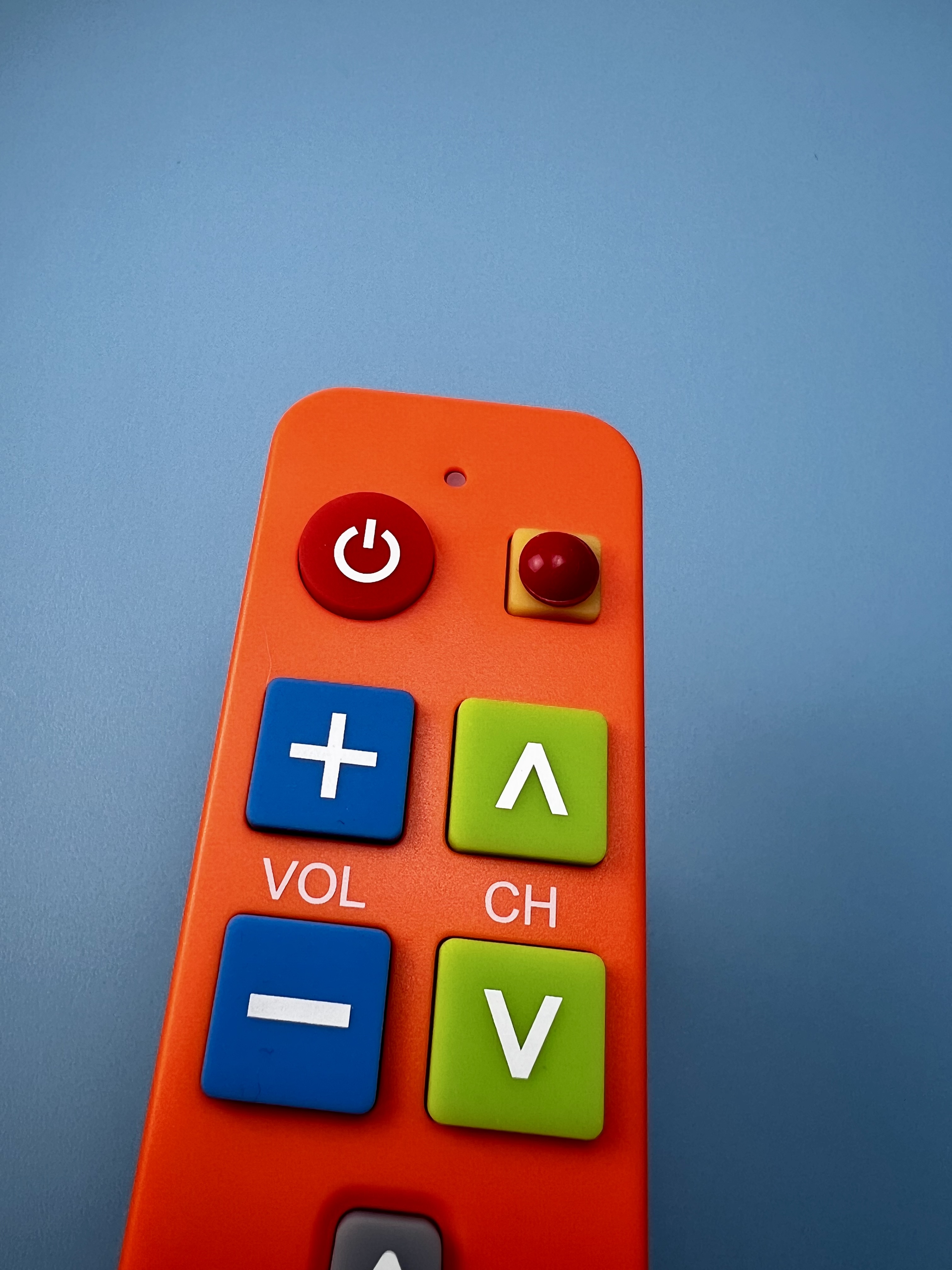 Orange remote with large colorful buttons and a raised tactile bump added near the top for easier identification by touch.