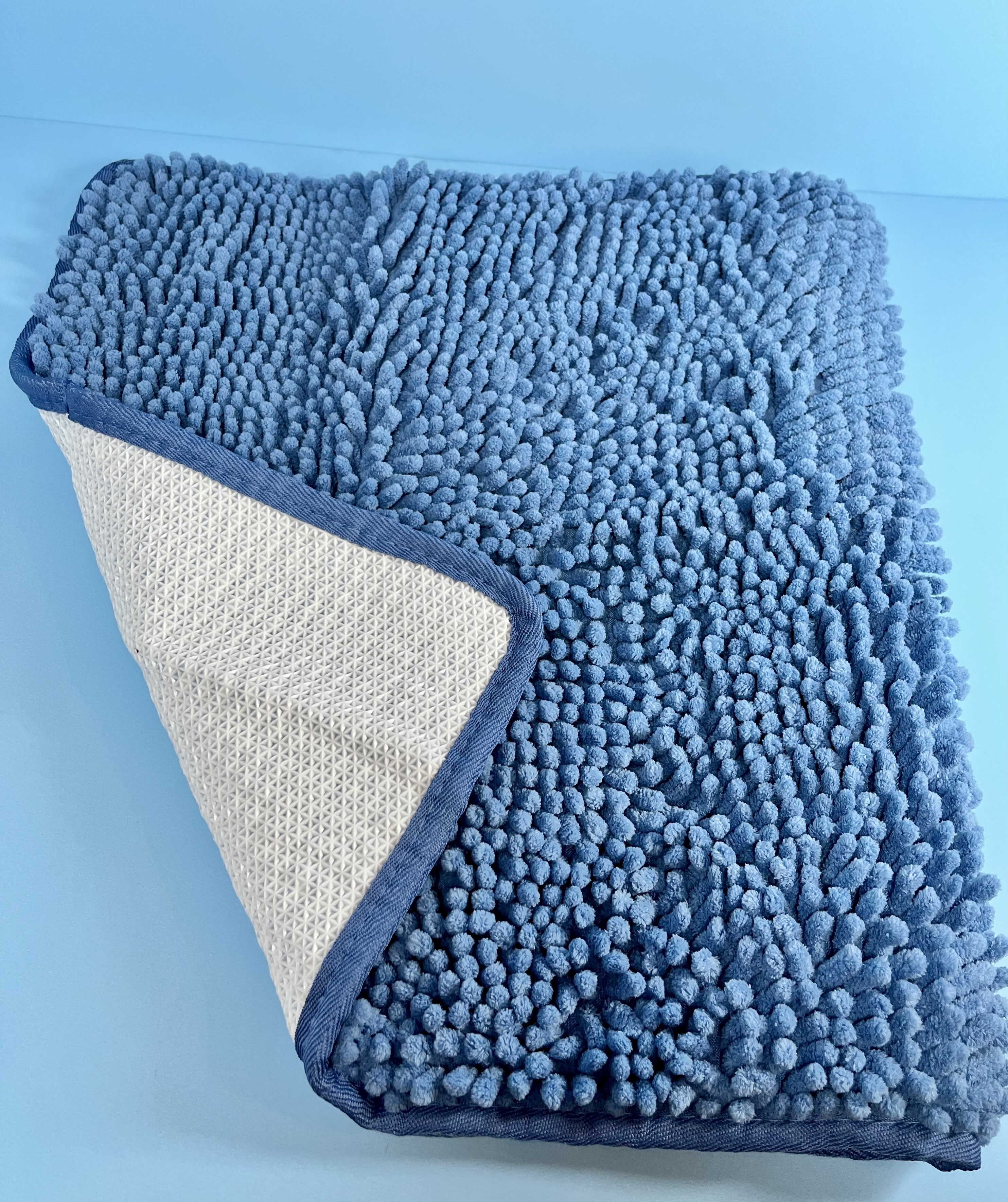 Blue textured bath mat with a rubberized non-slip backing to help reduce slipping on bathroom floors.