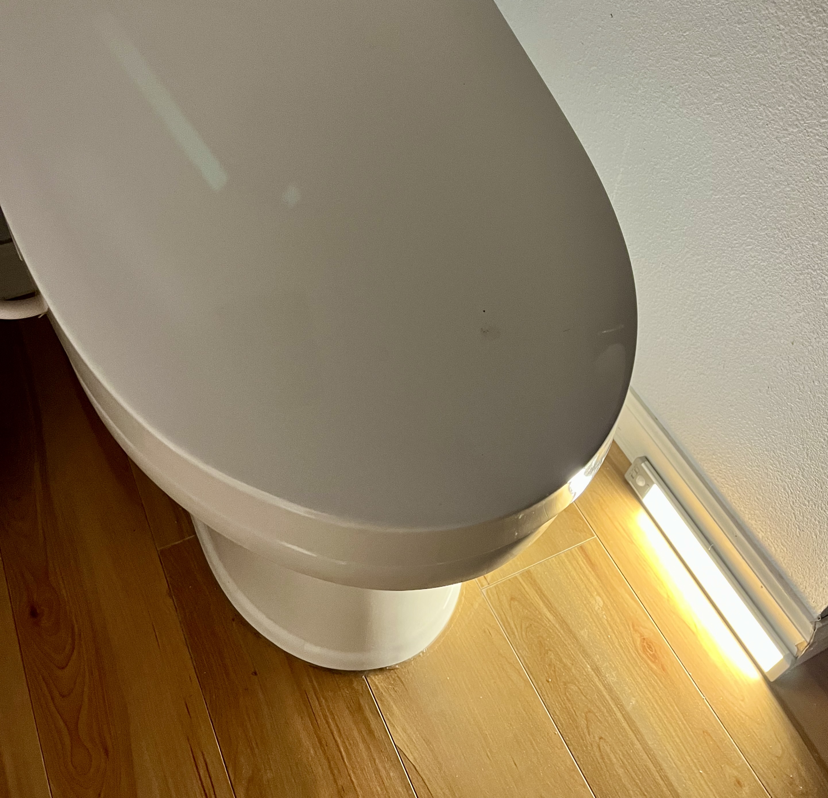 A strip of motion-activated lights beneath a toilet.