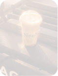 Niroo branded iced coffee in a clear plastic cup with a black straw on a dark surface.