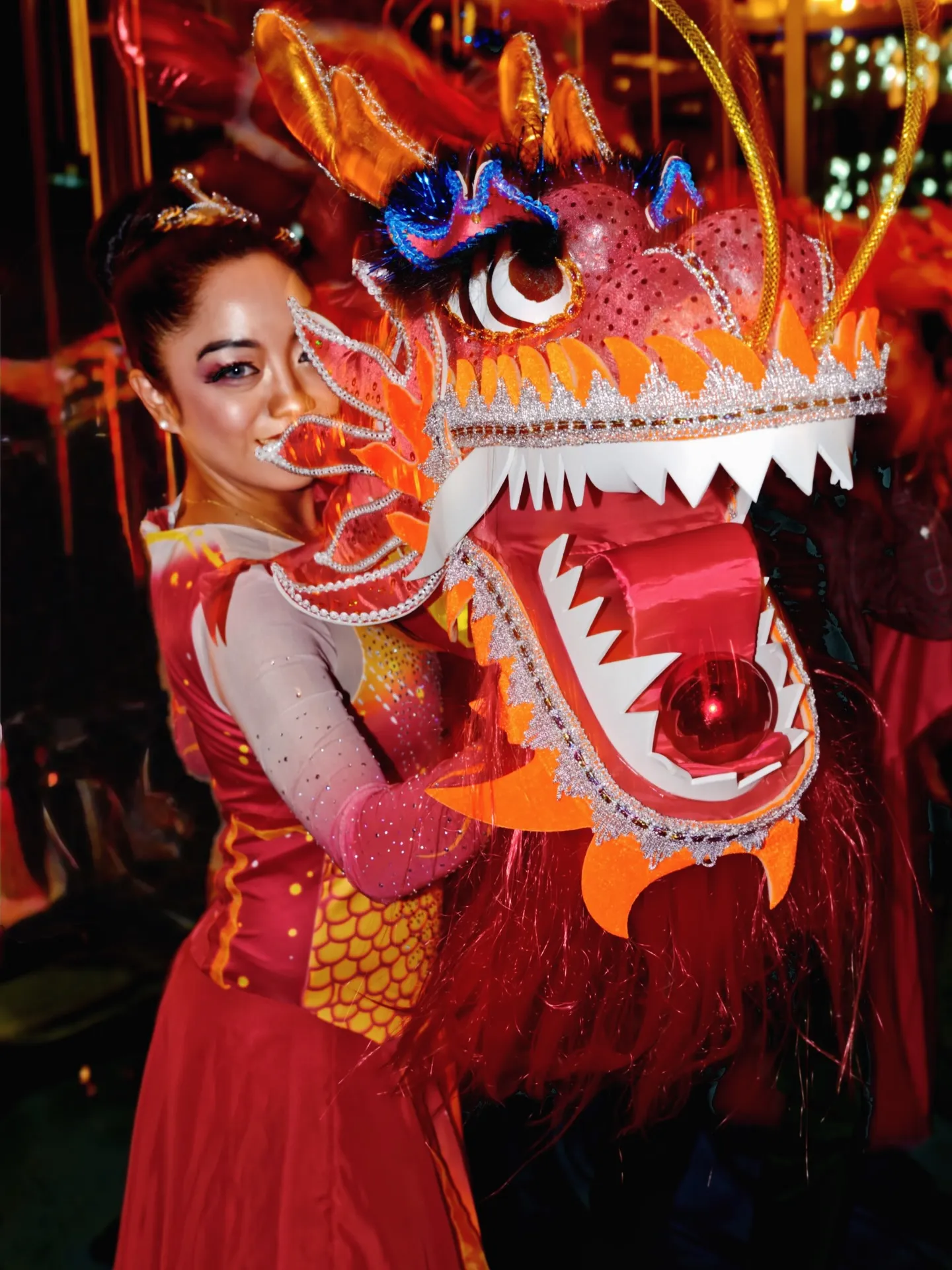 Performers in red costumes preparing for a traditional Chinese dragon dance with a brightly decorated dragon head.