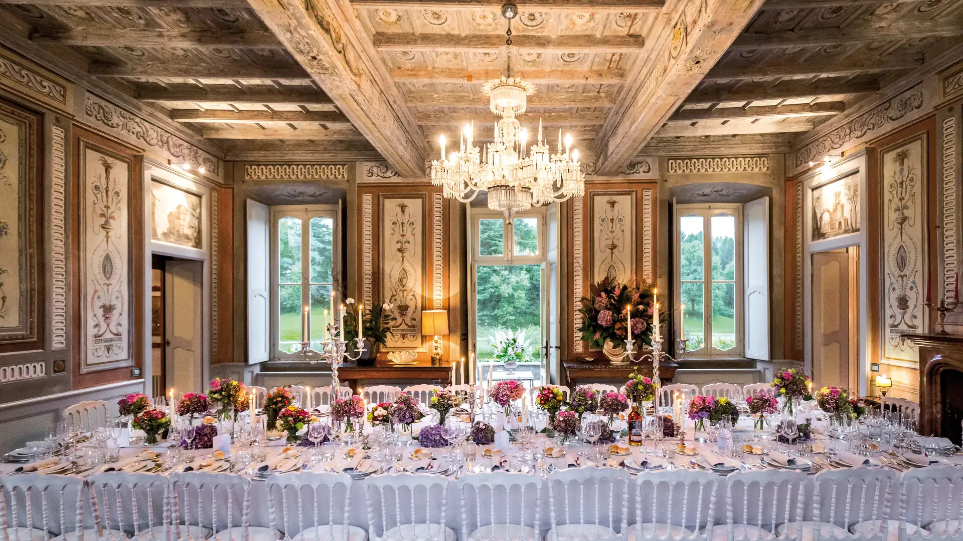 Frescoed hall at Villa Bossi set for dinner under a chandelier