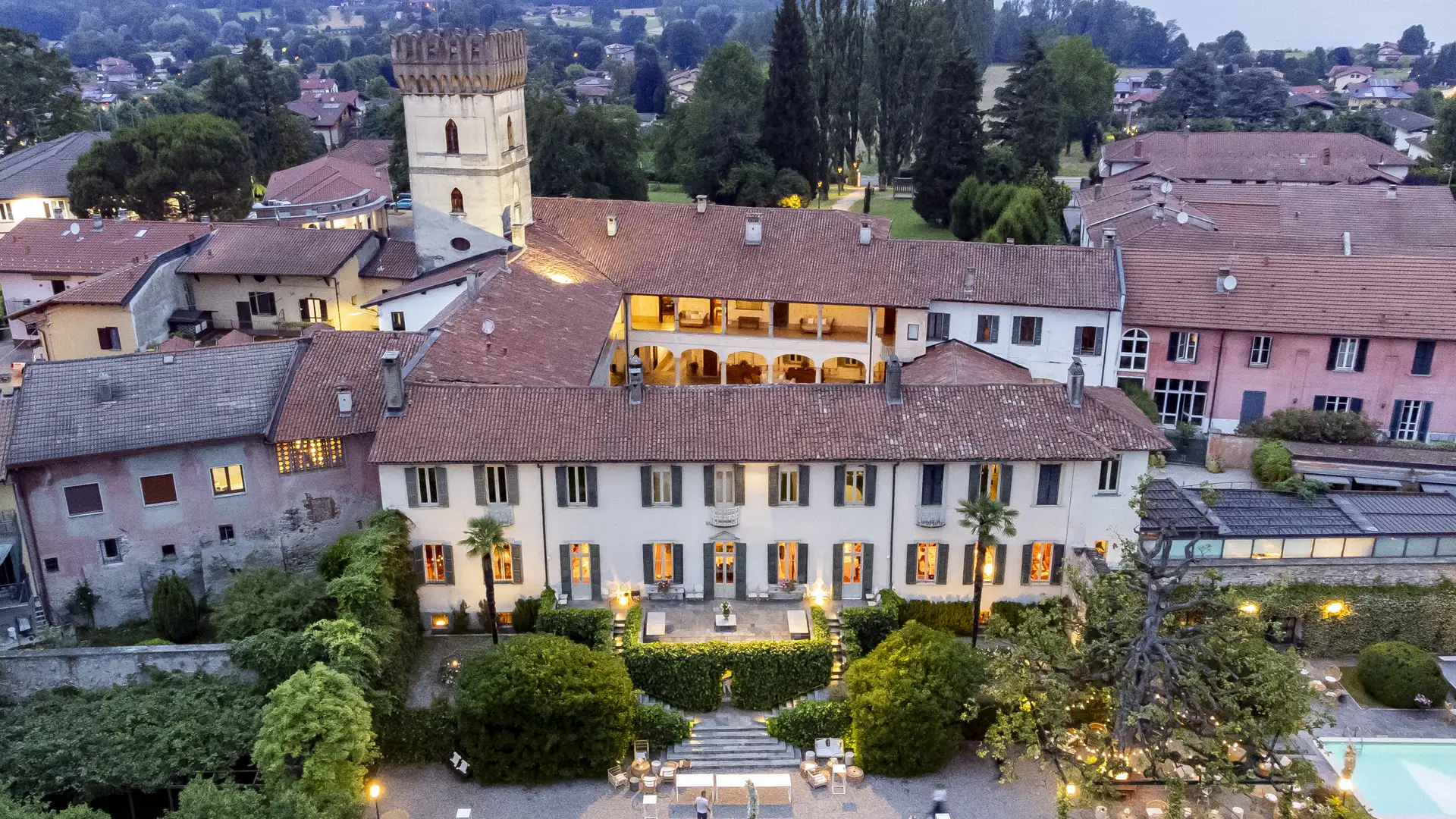 Villa Bossi lit at dusk with its tower above Lake Varese