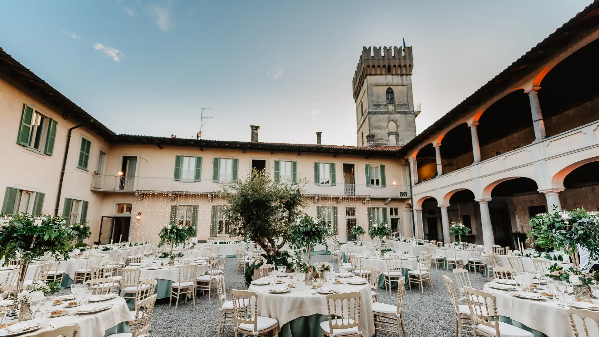 White banquet tables set in the arcaded courtyard of Villa Bossi