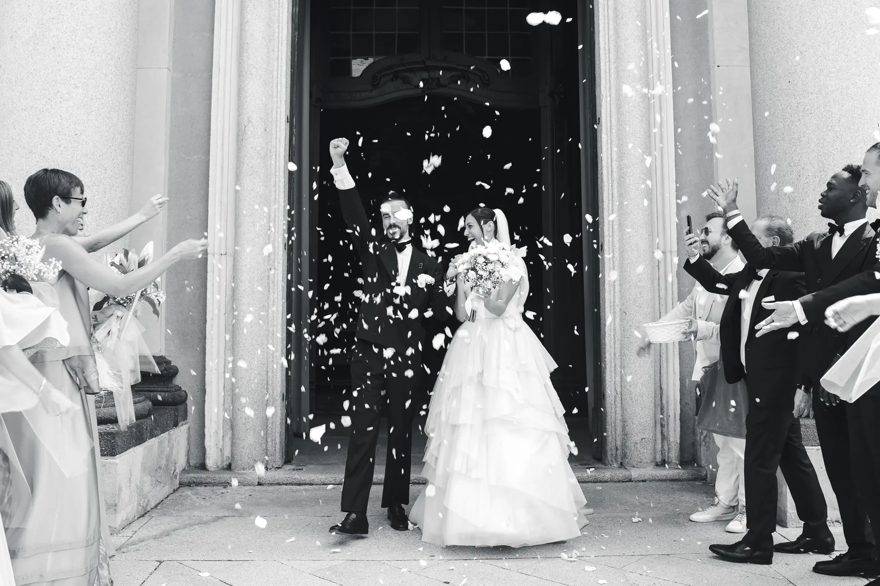 Bride and groom leaving the church under a shower of rice, black and white wedding photo