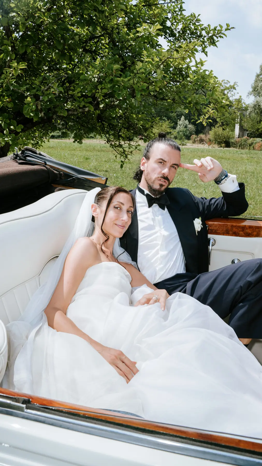Bride and groom relaxing in the open convertible after the ceremony
