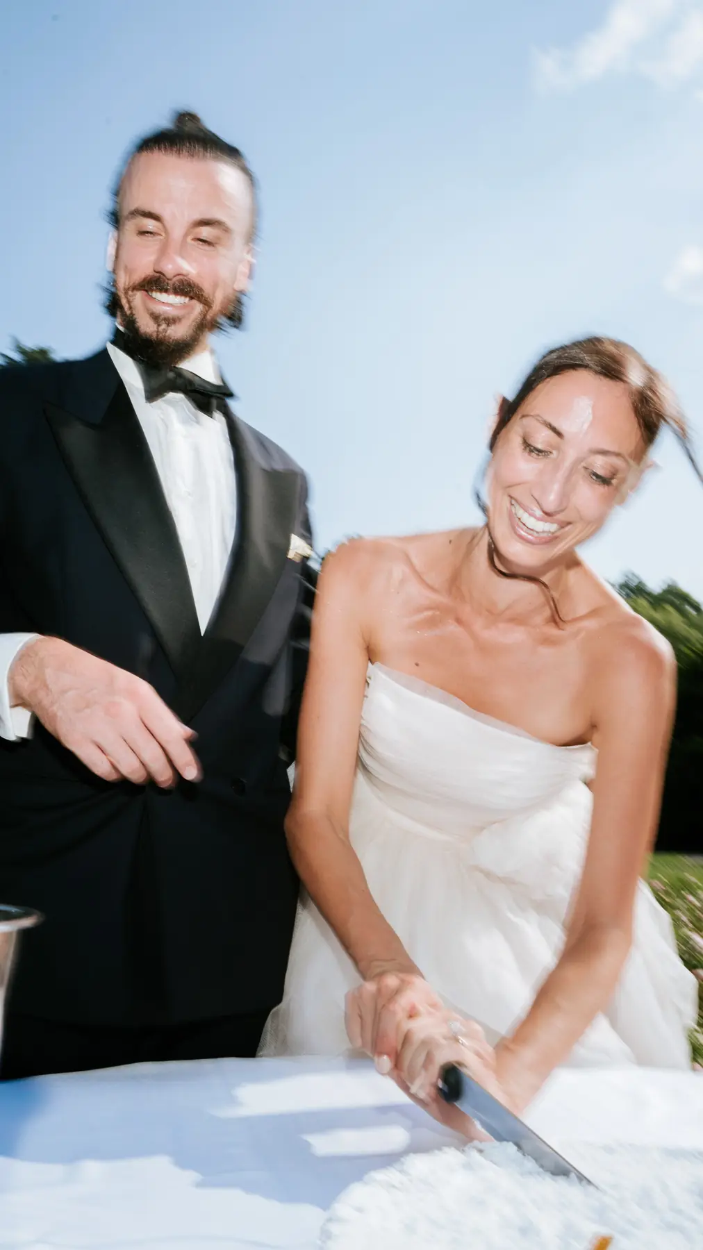 Bride and groom laughing while cutting the wedding cake