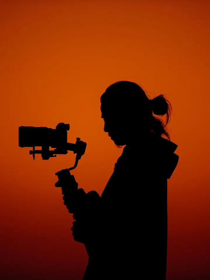 Camera operator filming an event in silhouette