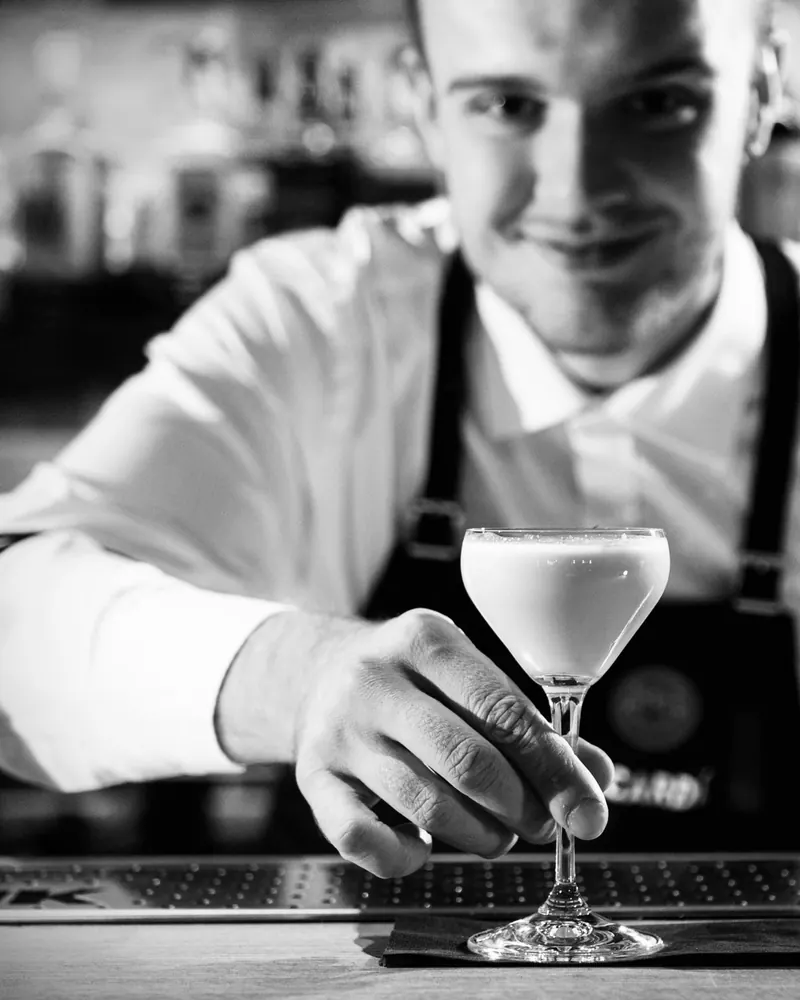Bartender from the Cover Page Agency roster serving a cocktail, black and white portrait
