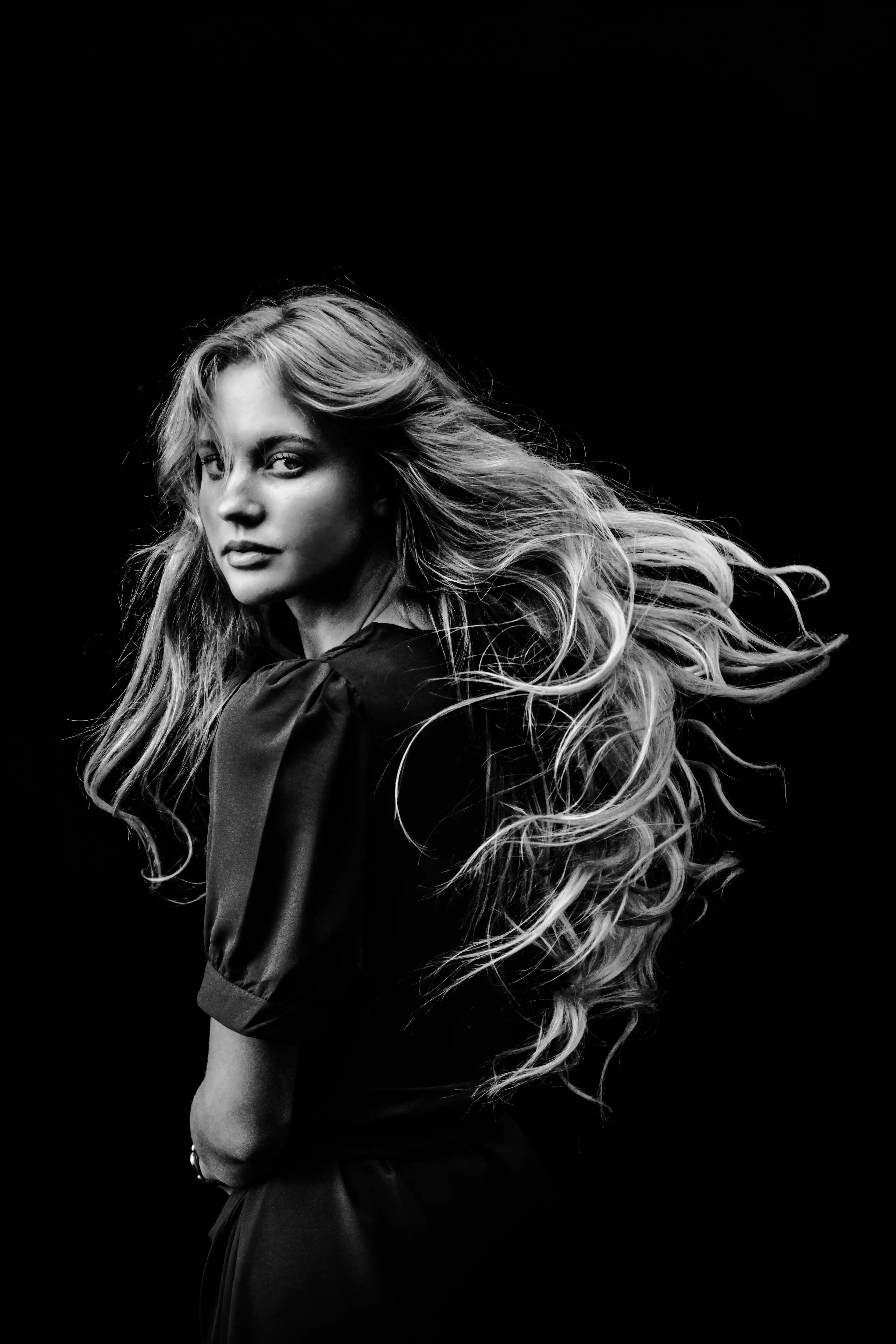 Elegant wavy-haired performer in black and white portrait for hairdresser talent at Coverpage Dubai.