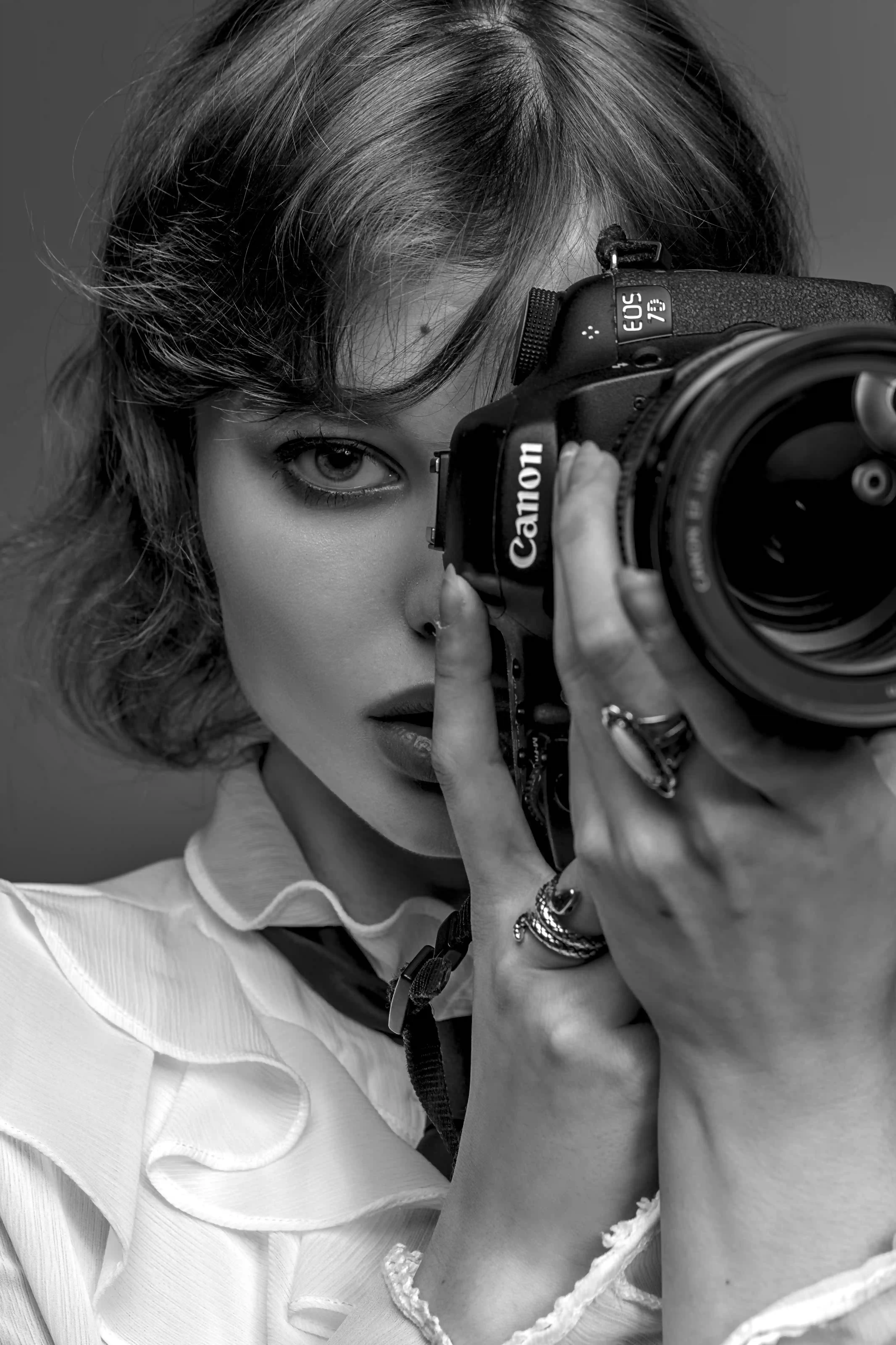 Elegant photographer talent holding Canon camera in black and white portrait for Coverpage Dubai entertainment agency.
