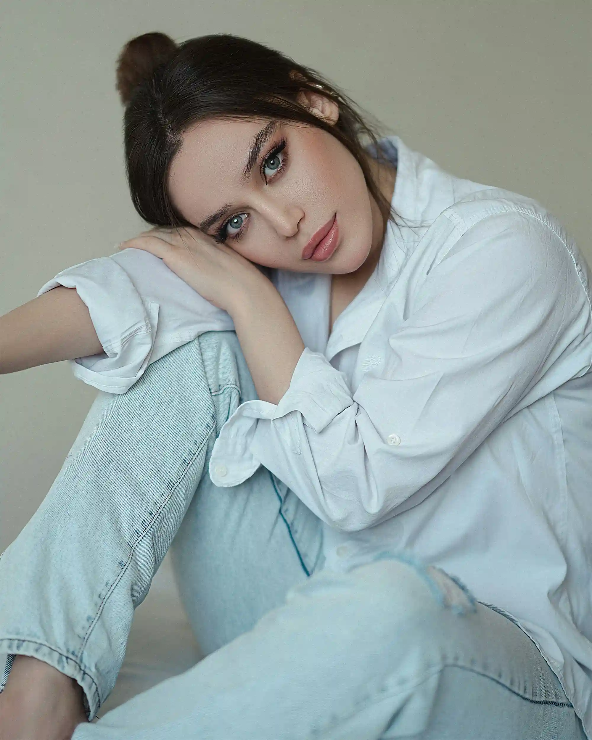 Elegant model talent leaning on pillar in white coat and black scarf for Coverpage Dubai luxury fashion showcase.