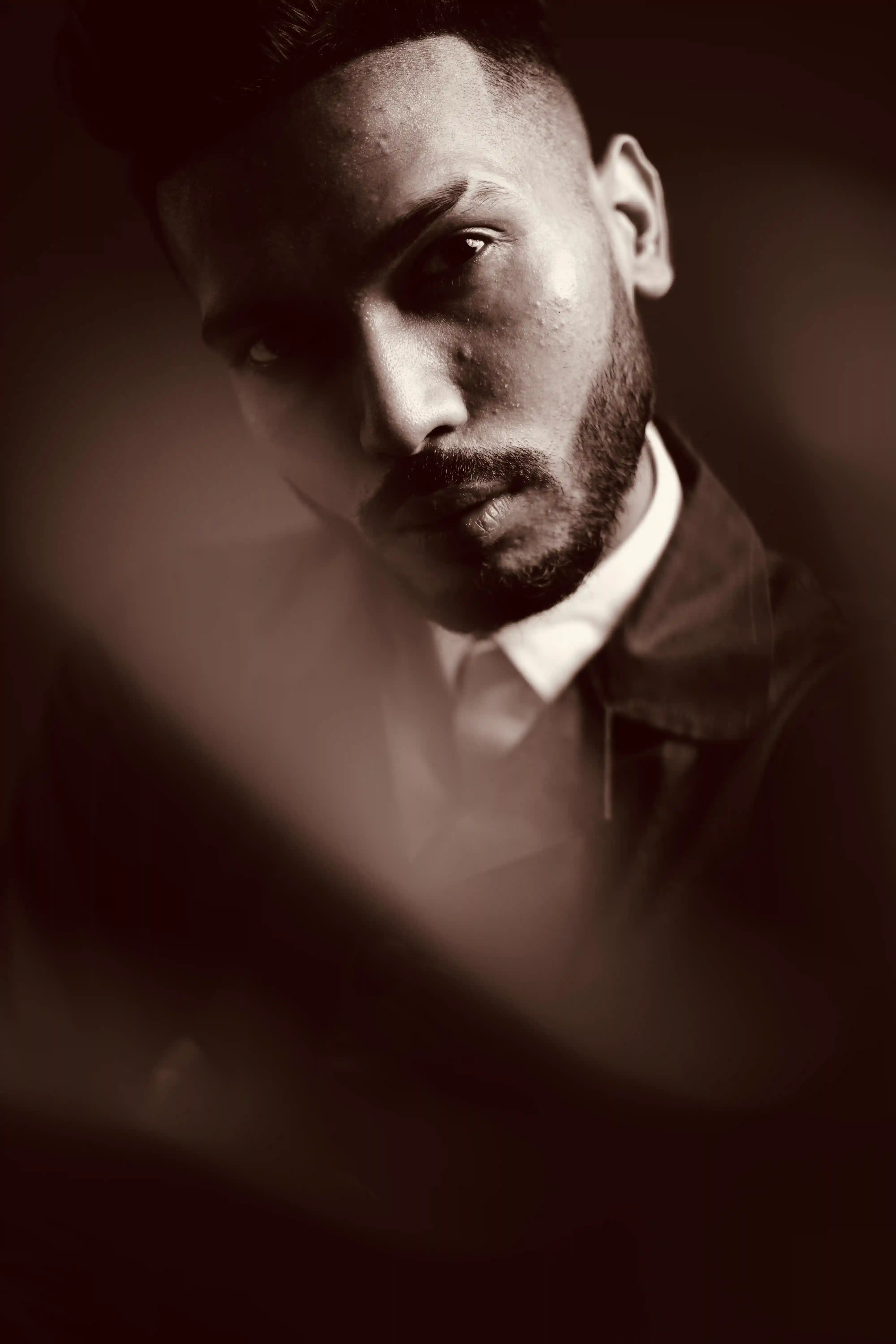 Dramatic security talent in dark suit with white watch posing in sepia portrait for Coverpage Dubai luxury agency.