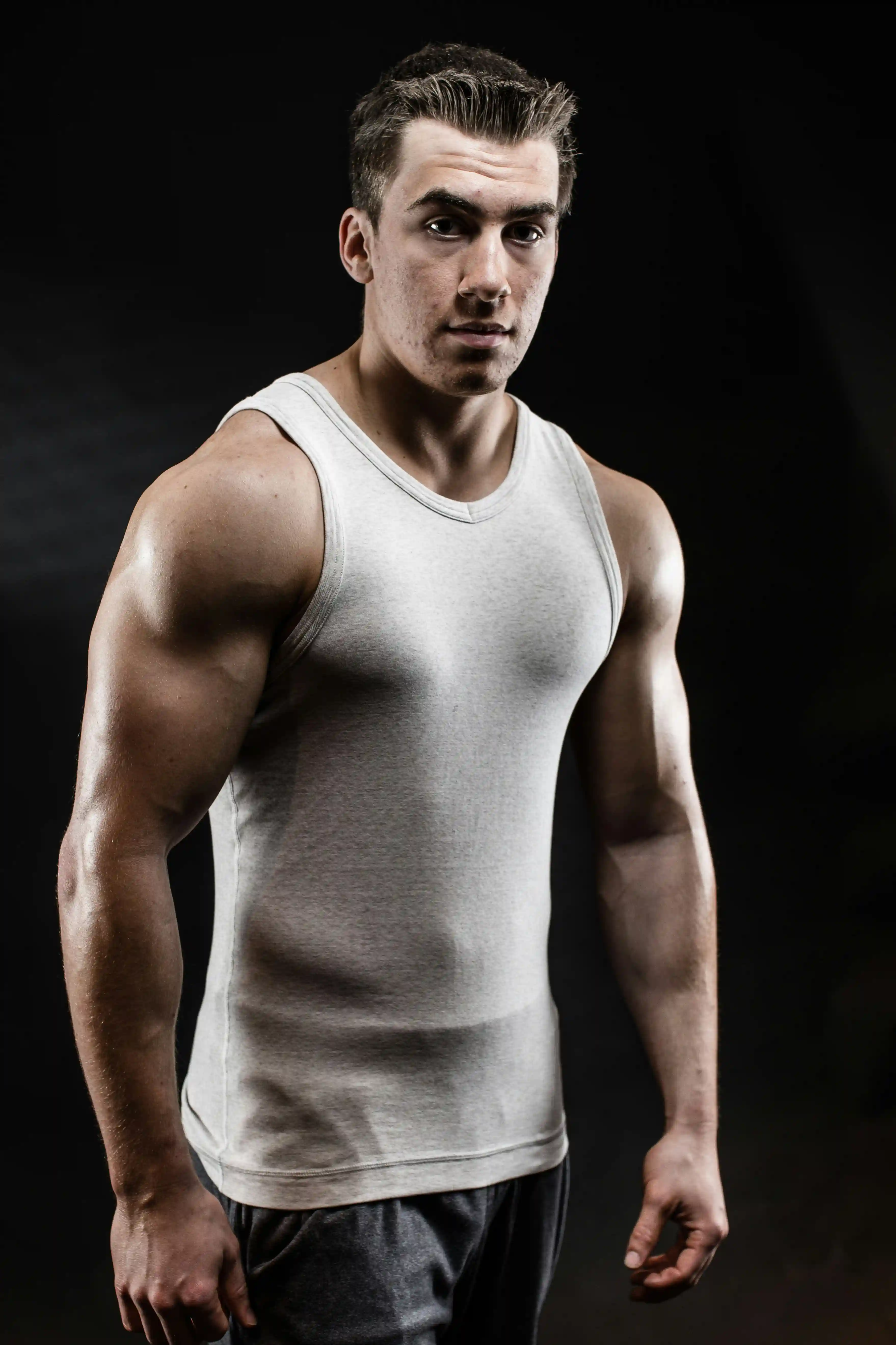Cover Page muscular security agent in white tank top, serious pose with defined arms, on dark background.