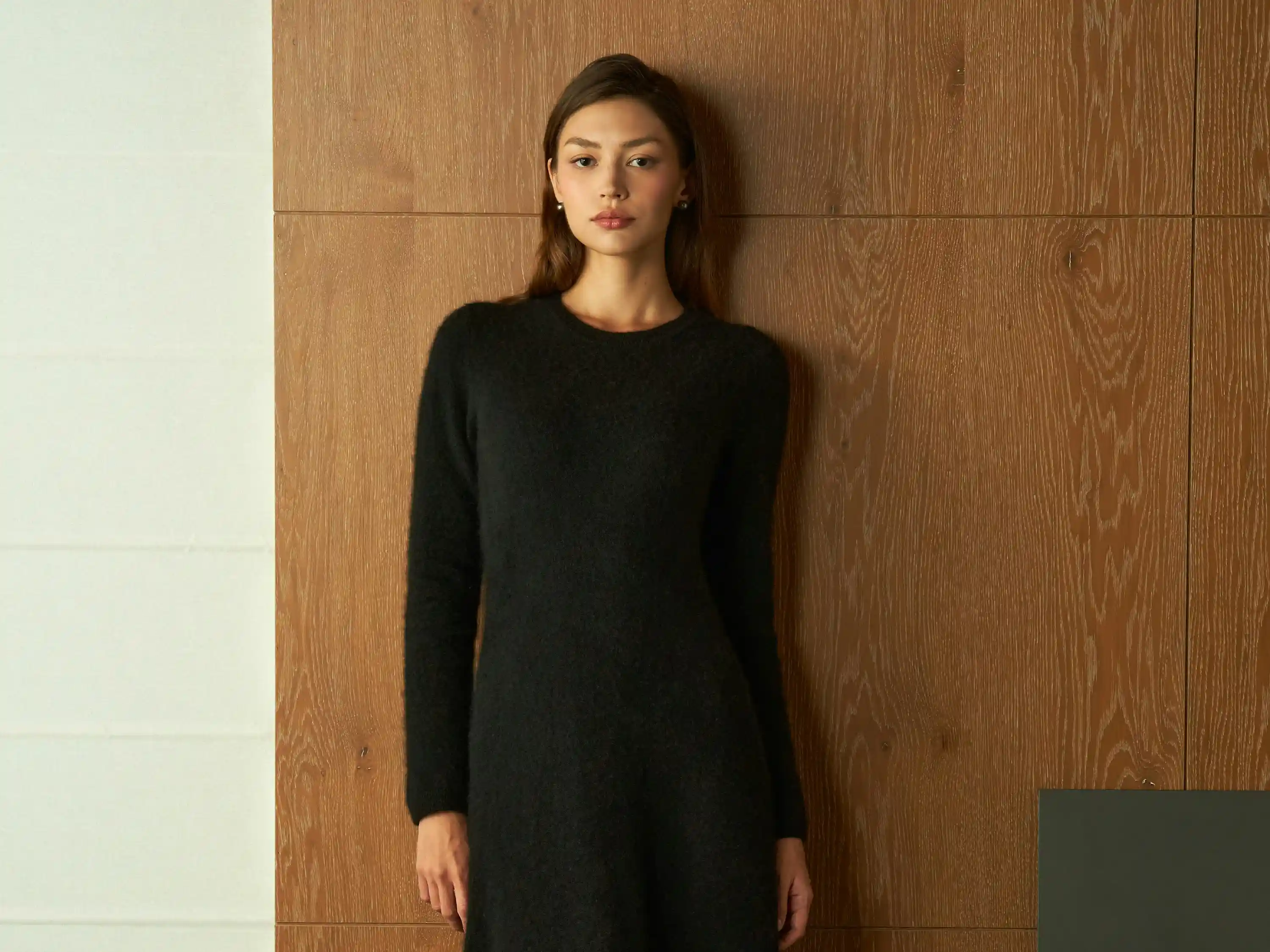 Cover Page elegant waitress in black long-sleeve midi dress, posing against wooden paneled wall in sophisticated setting.