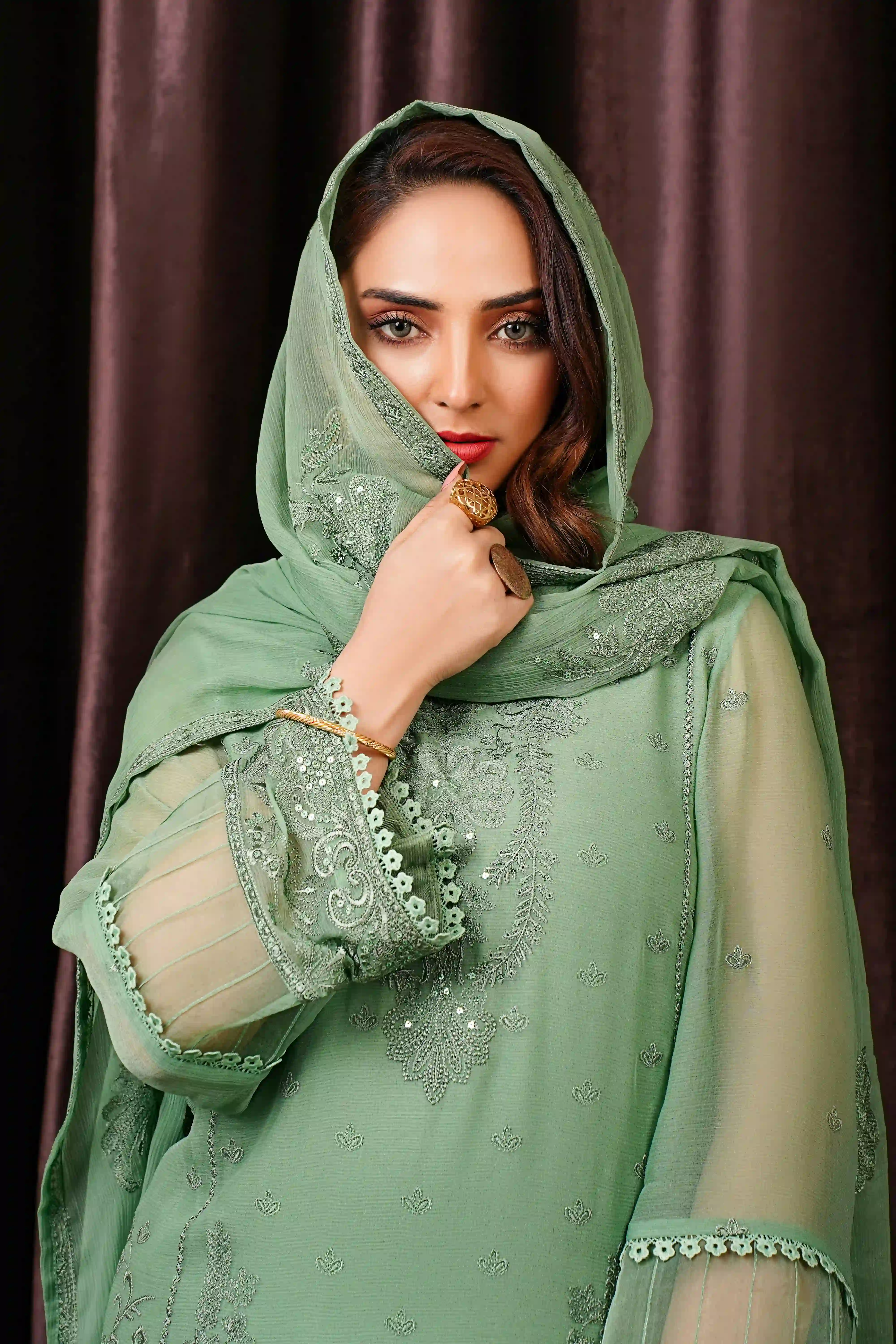 Cover Page model in light beige abaya and hijab, posing with hand on head in full-length studio shot on white background.