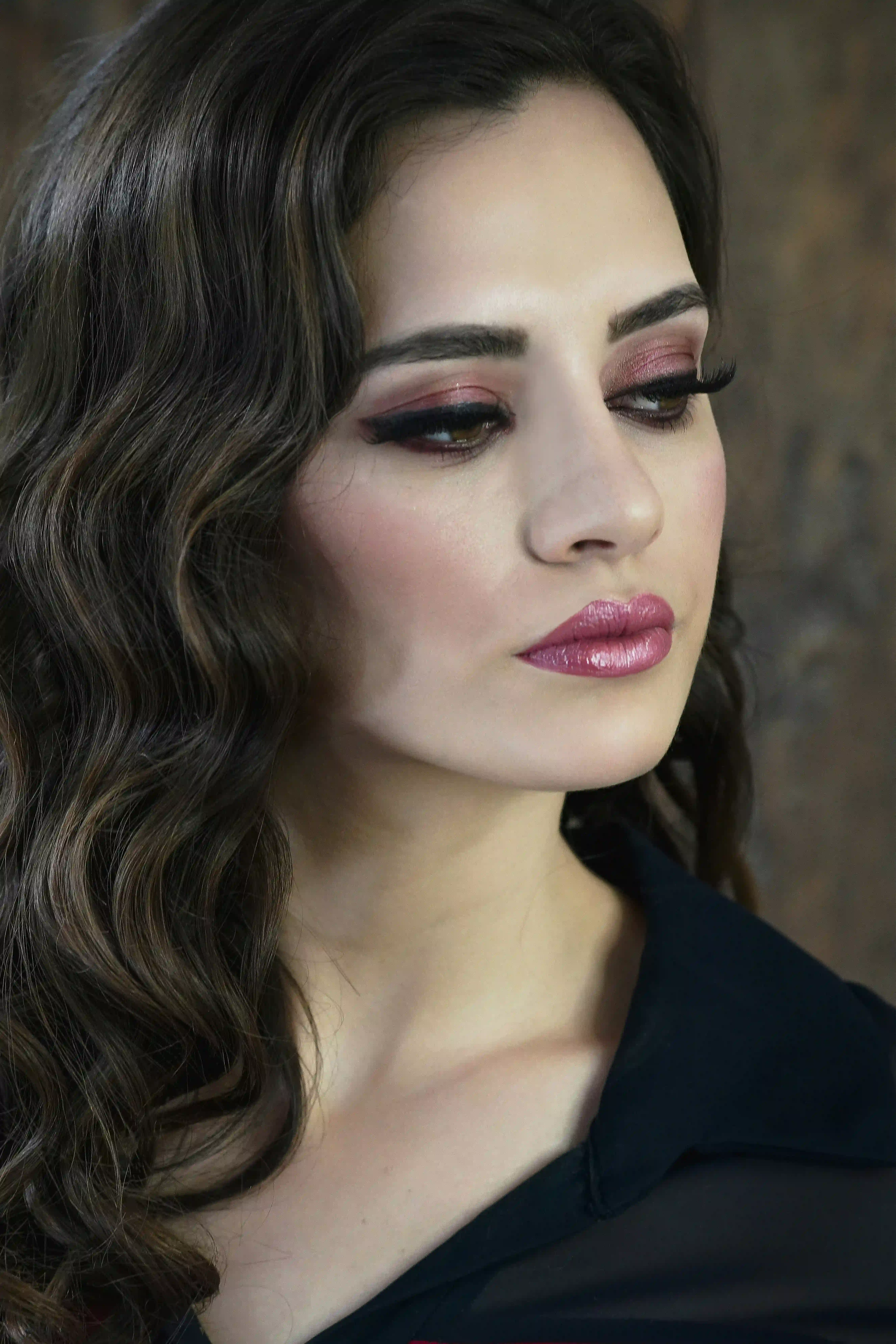 Cover Page model with wavy brown hair, pink eyeshadow and glossy lips, side profile on wooden background.