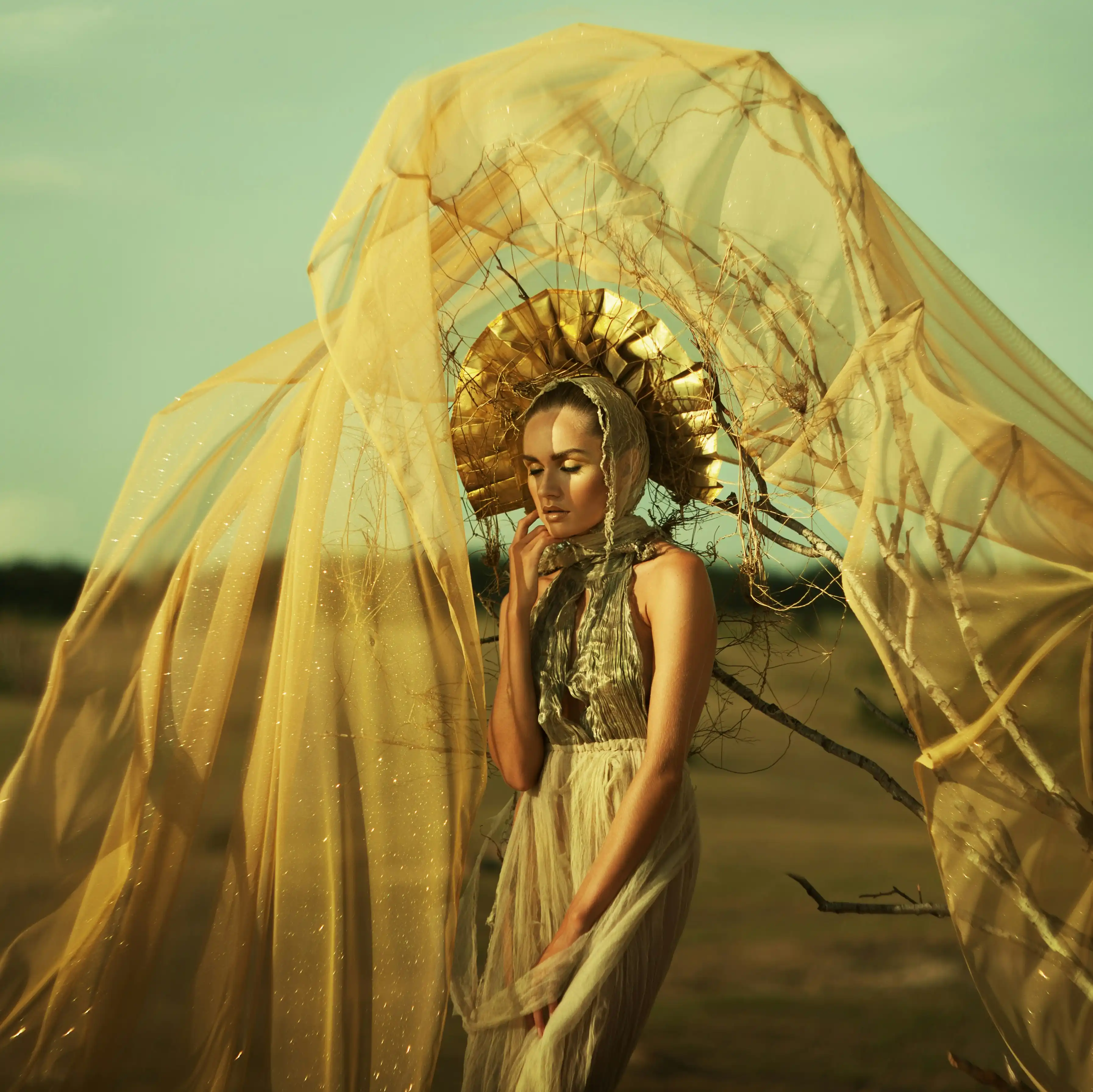 Cover Page model in gold fringed dress, standing in ornate arched doorway of historic hall with dramatic lighting.