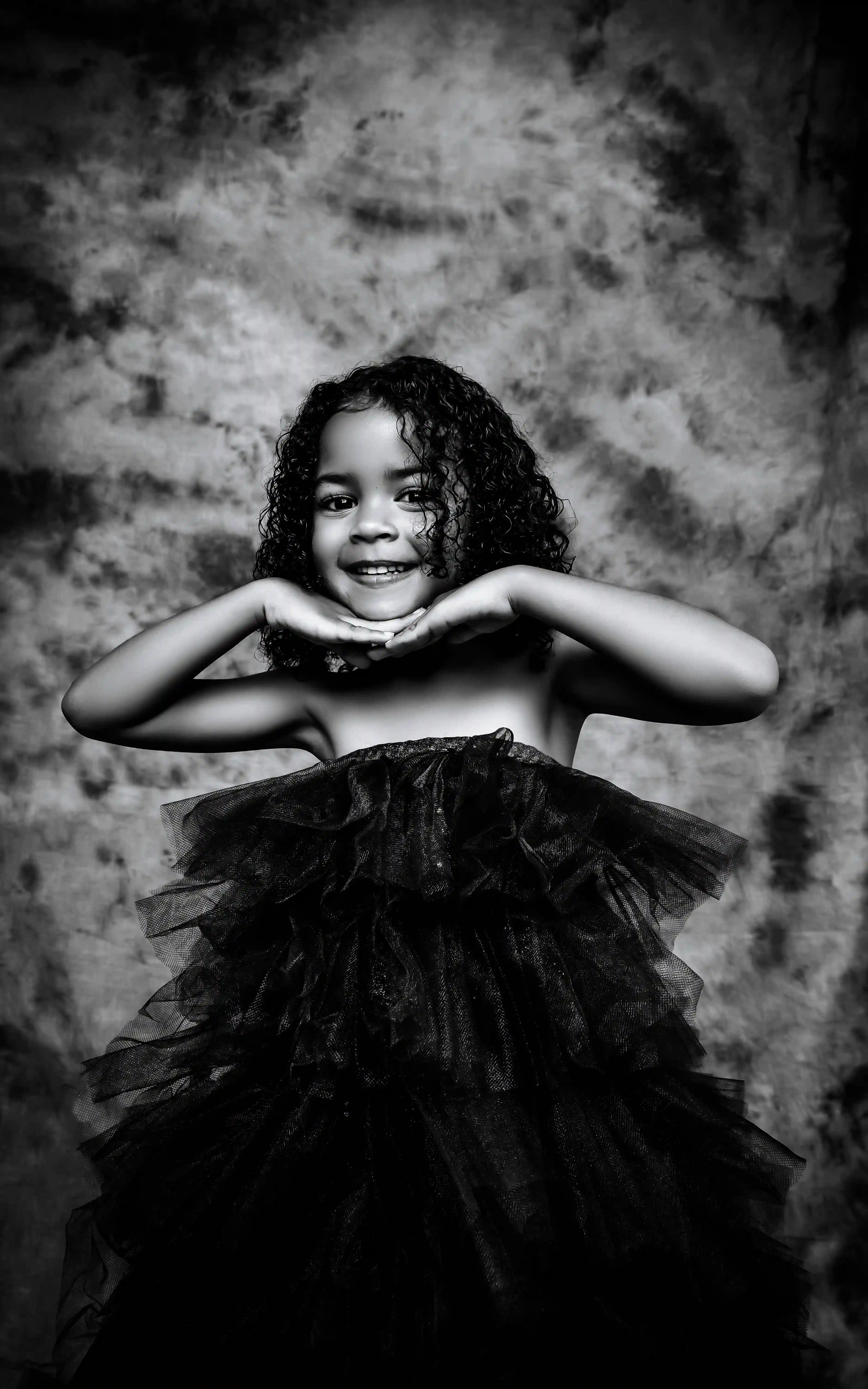 Cover Page young model in black leotard, sitting cross-legged with hand under chin, thoughtful pose on white background.