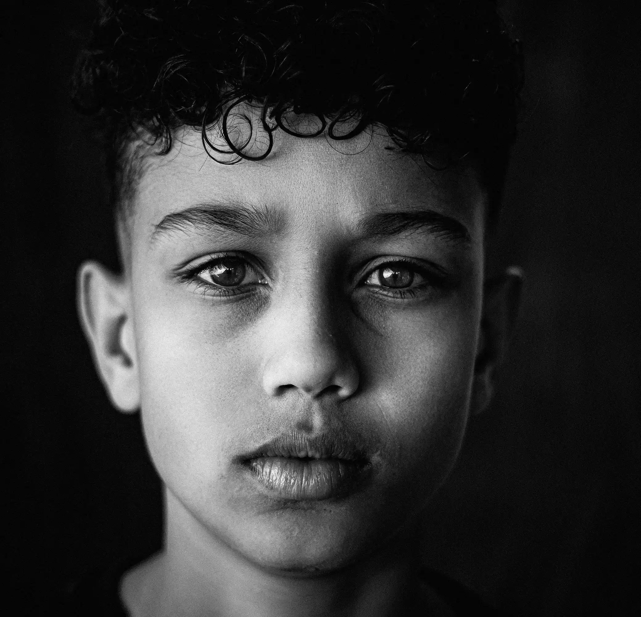 Cover Page smiling young model with curly hair in black tulle dress, hands under chin in playful pose, black and white on textured gray background.