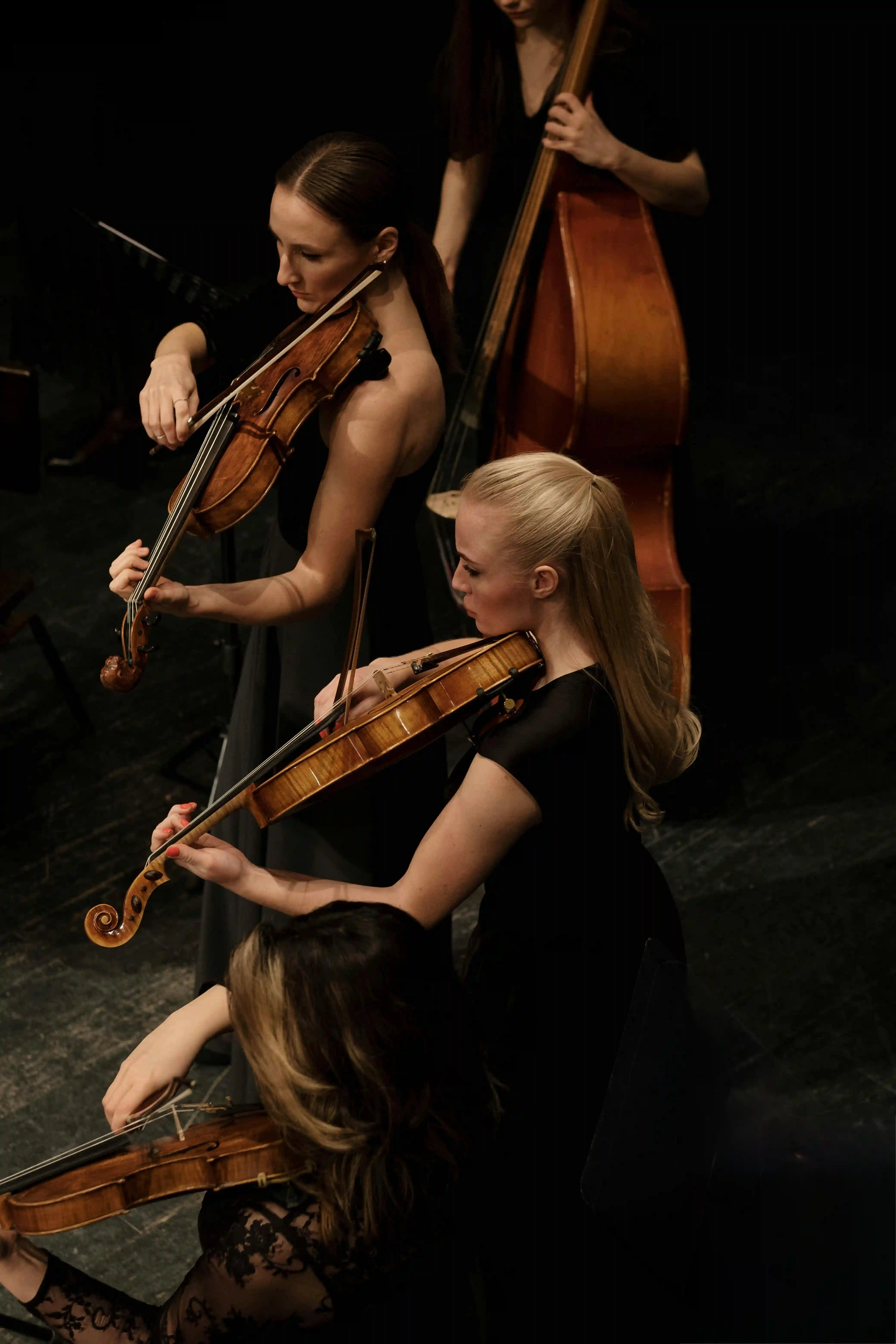 Elegant luxury string quartet in sophisticated black attire passionately playing violins and double bass for Cover Page Agency Dubai. High-end classical music ensemble delivering refined, world-class live performances at exclusive events, galas and luxury soirées across the UAE.