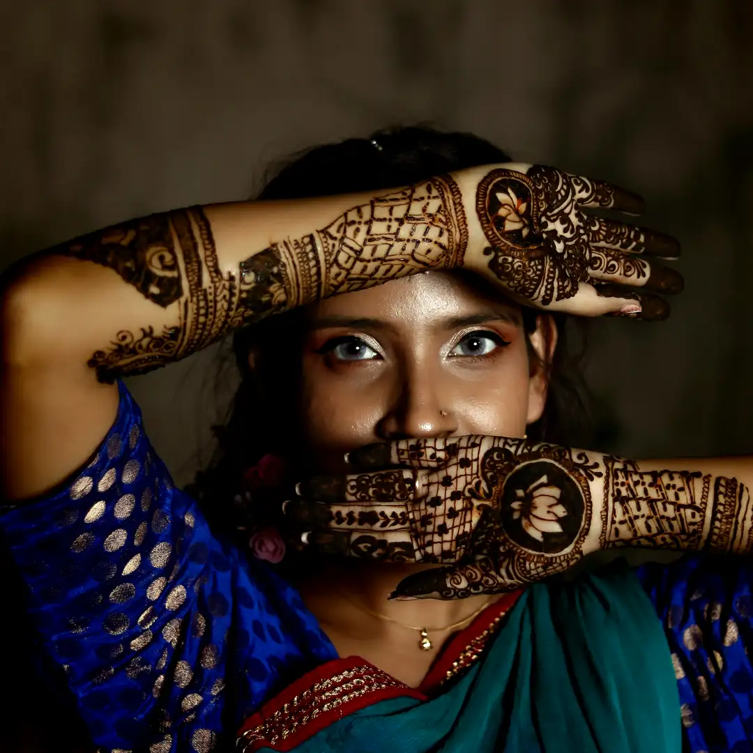 Striking Indian model with intricate bridal mehndi designs on hands and arms, floral lotus motifs and geometric patterns, framing her face in elegant pose. Traditional blue saree with golden accents. Cultural entertainment photoshoot by Cover Page Agency Dubai. Perfect for Indian weddings, mehndi nights, desi events, luxury parties, and Bollywood-themed activations in UAE.