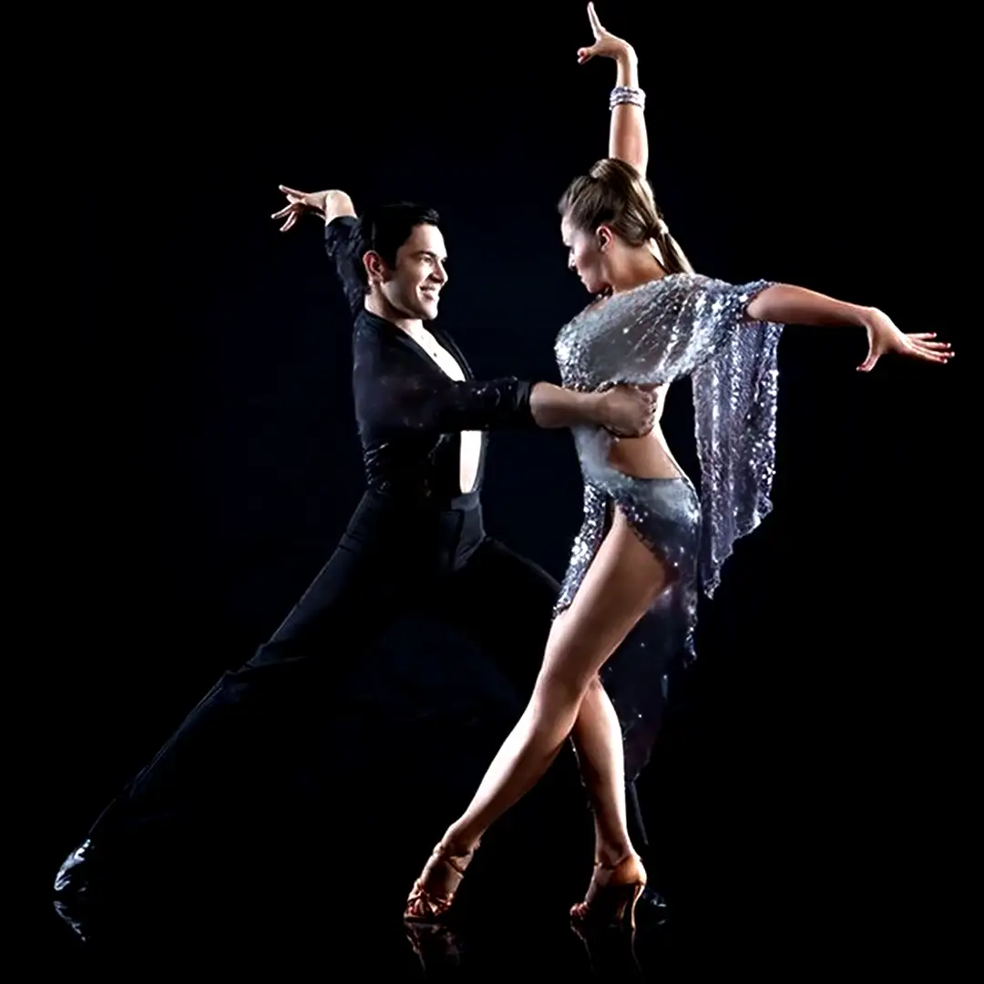 Passionate luxury salsa dancers in dazzling white fringe costume and sharp black attire performing a high-energy lift and kick for Cover Page Agency Dubai. High-end Latin dance entertainment talent delivering sensual, rhythmic and show-stopping performances at exclusive events and luxury parties across the UAE.