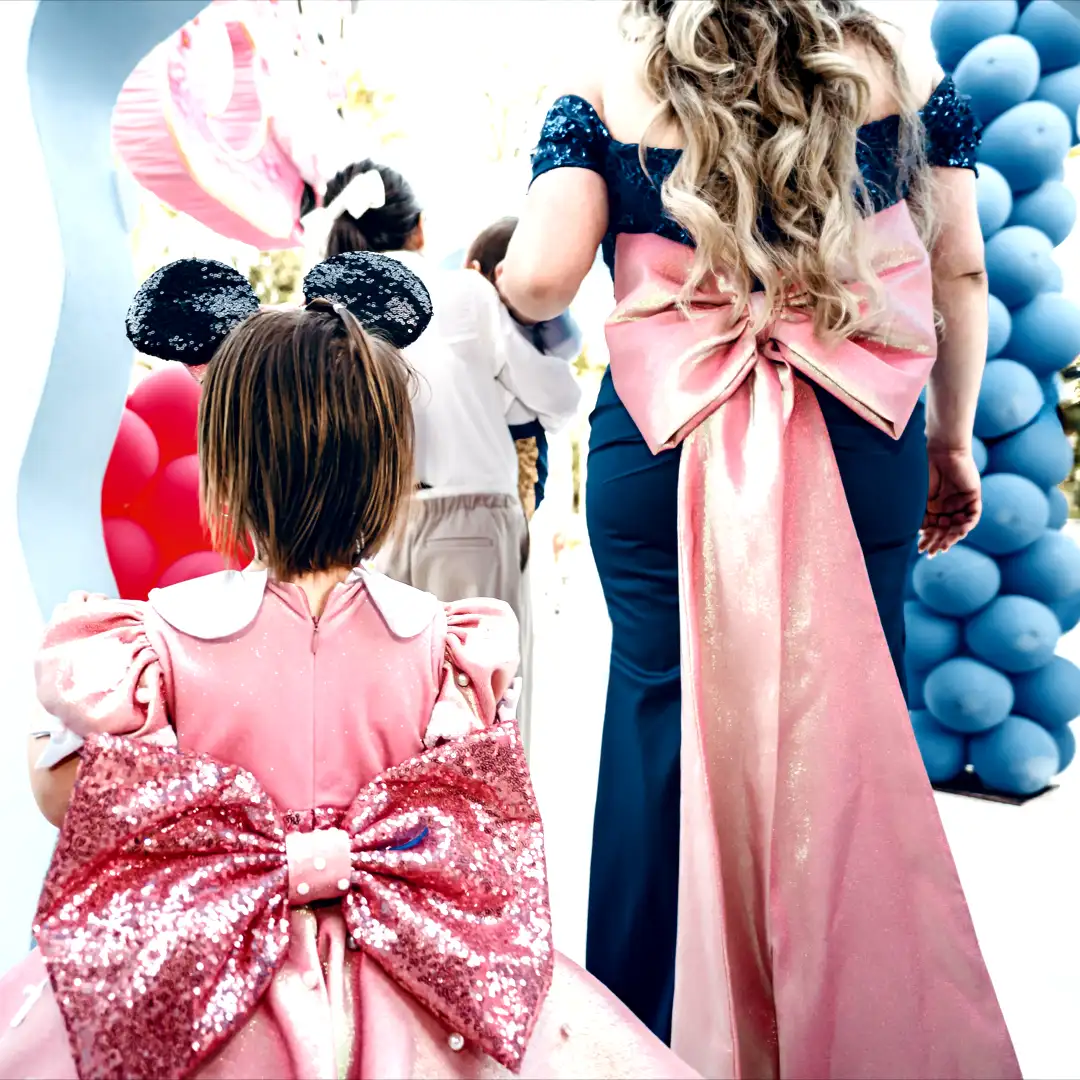 Cover Page Dubai - Young girl in pink sequin dress with bow at a luxury kids event surrounded by blue and pink balloon decor in Dubai