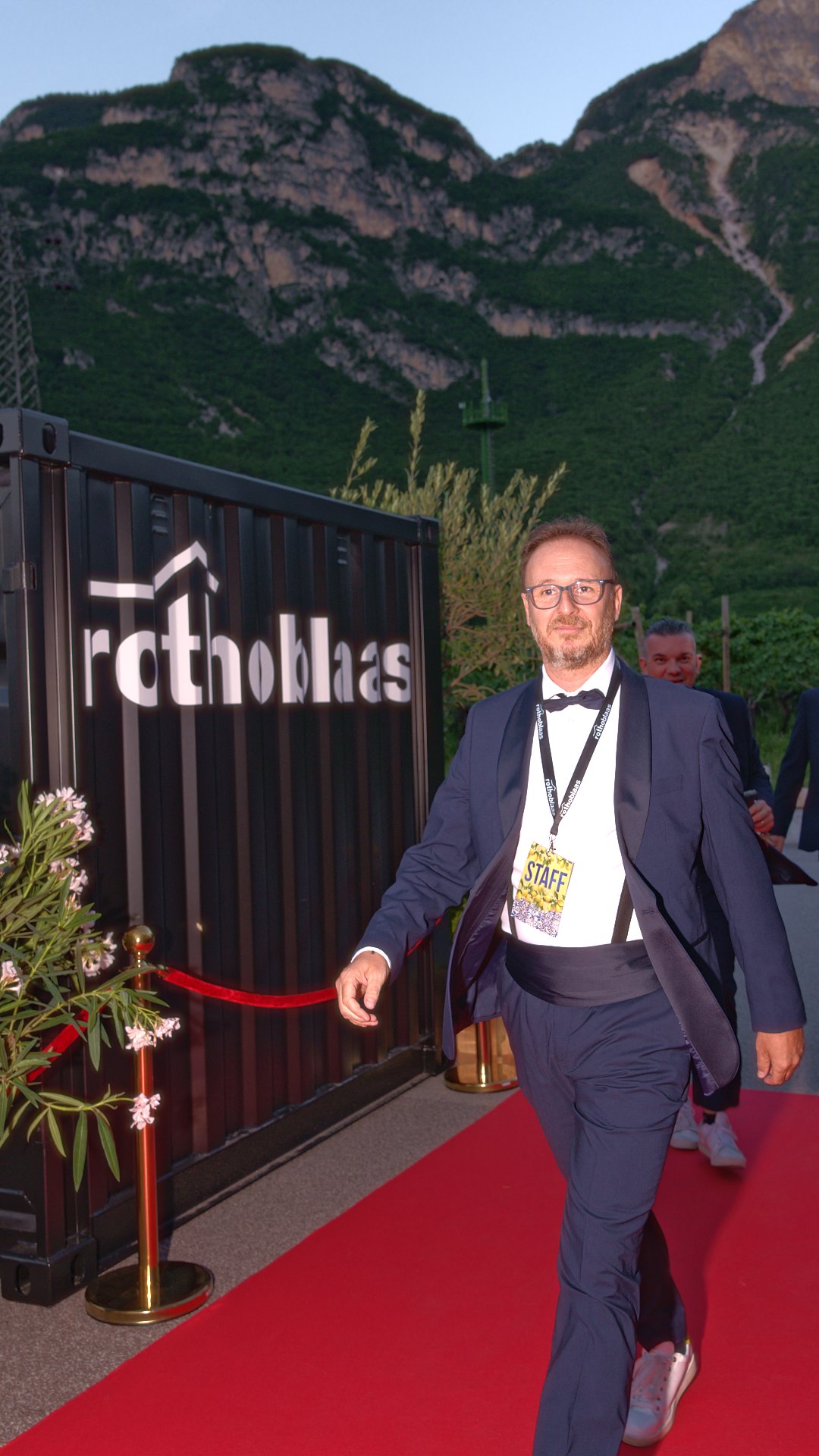 Membro dello staff in smoking con badge cammina sul red carpet a un evento aziendale