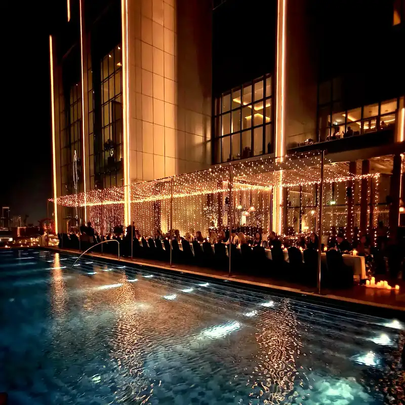 Fairy light canopy over a poolside dinner at night