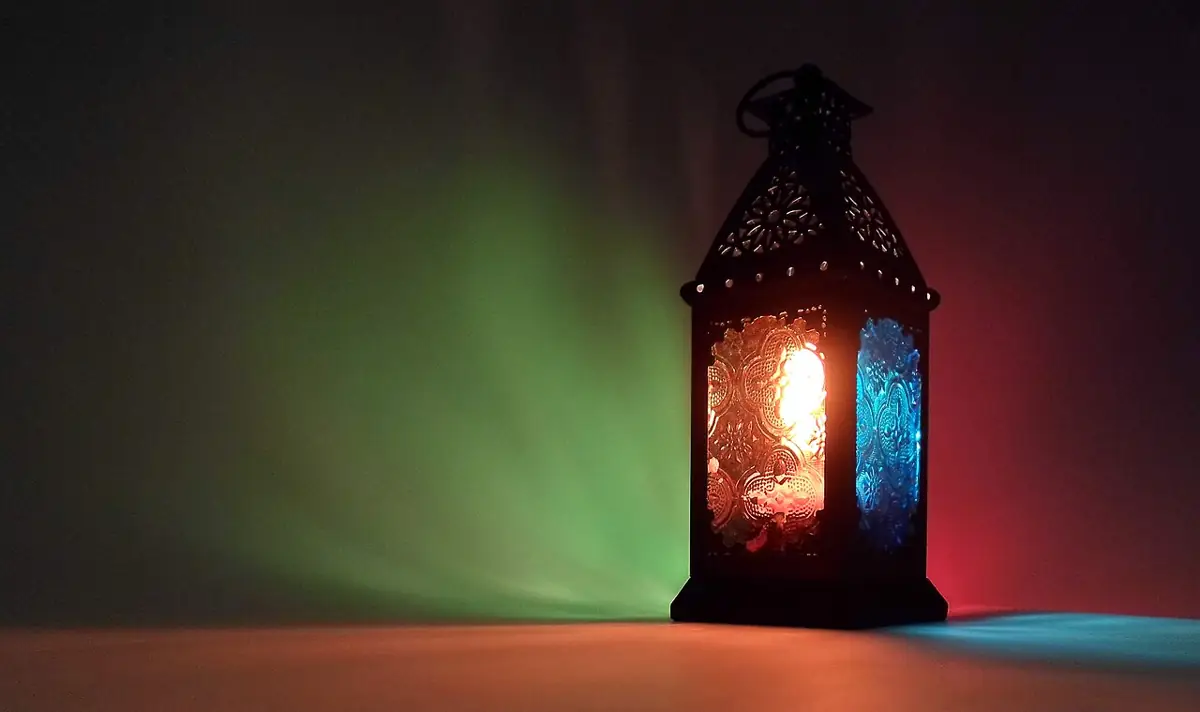 Glowing Ramadan lantern with coloured glass panels on a dark background