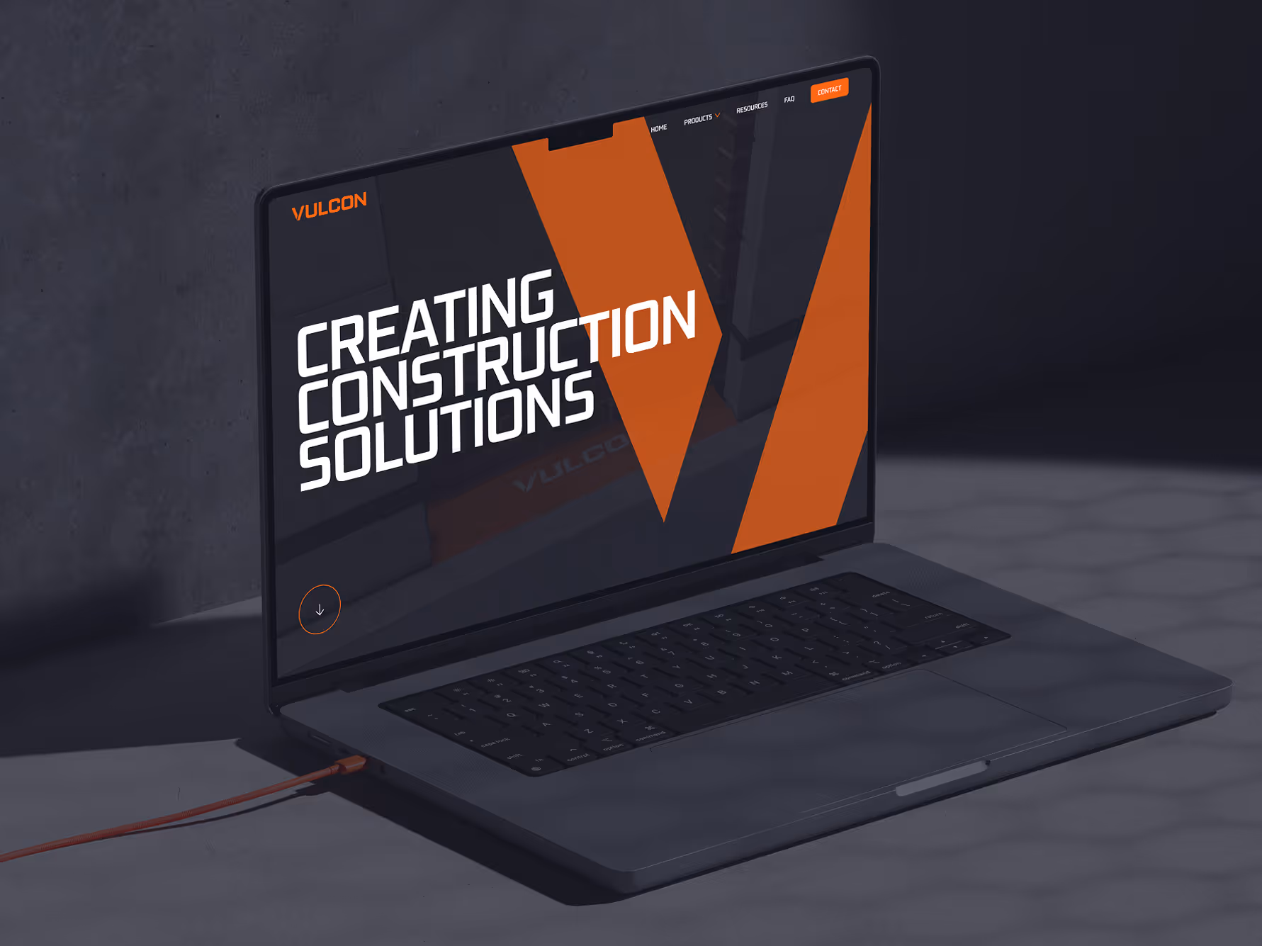 Laptop on gray surface displaying Vulcon site with text creating construction solutions and orange design.
