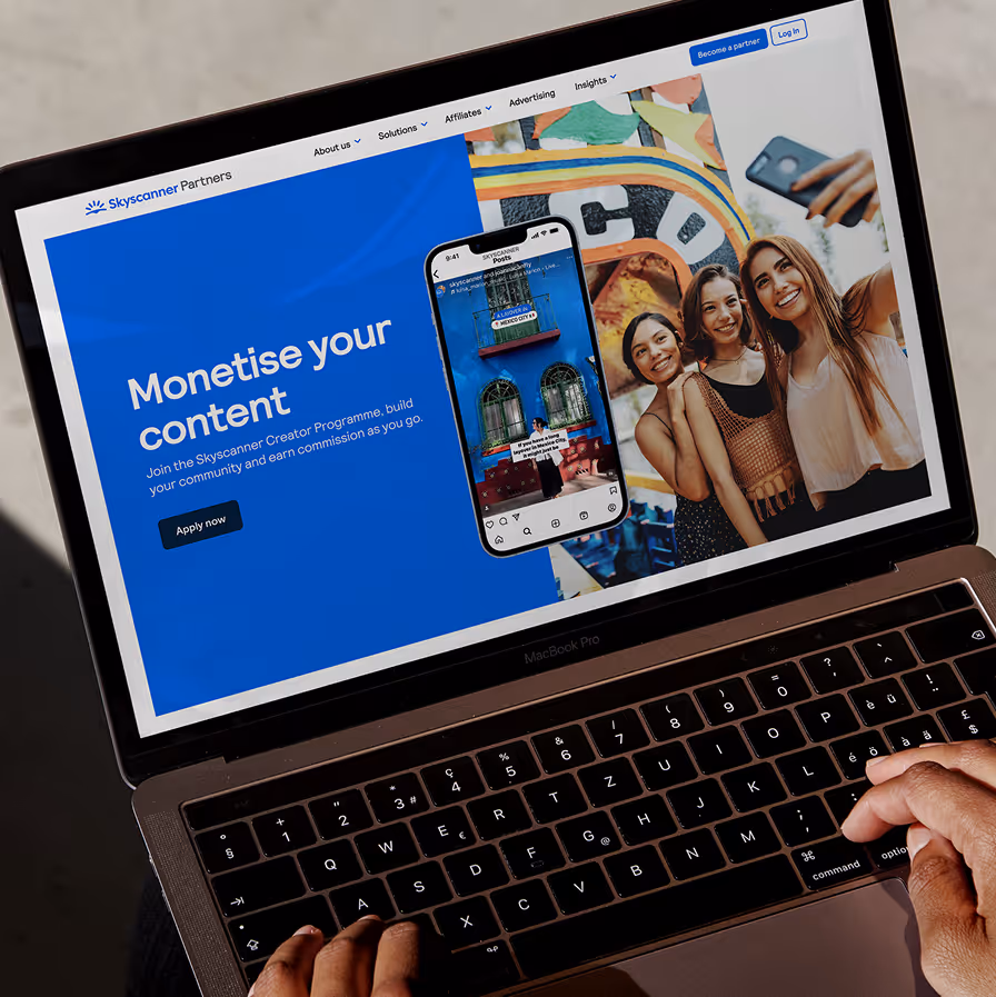 Laptop screen shows Skyscanner Partners page inviting users to monetise content and join creator program.