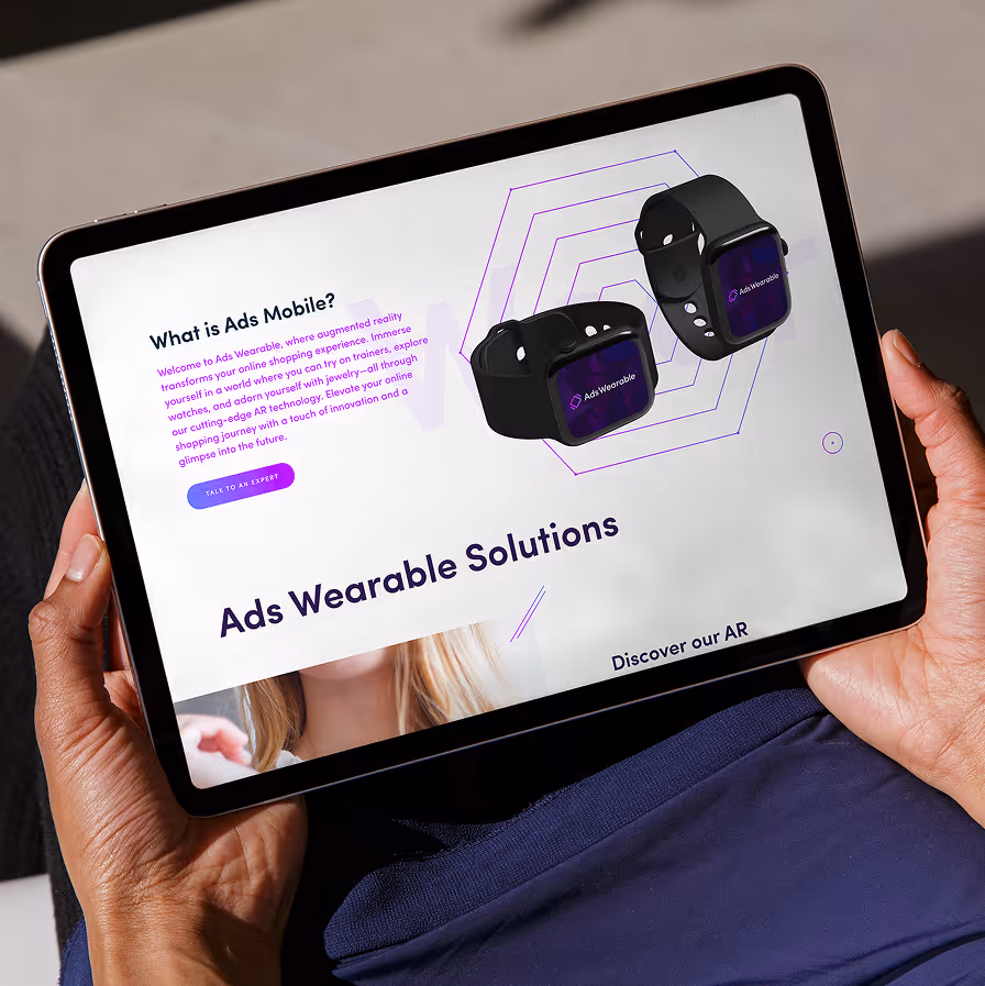 Person holding a tablet displaying an Ads Wearable Solutions page with two smartwatches and text about AR shopping.