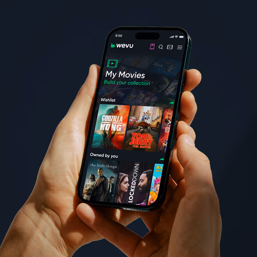 Hand holding phone showing a movie app with wishlist and owned movies like Godzilla vs Kong and Tom & Jerry.