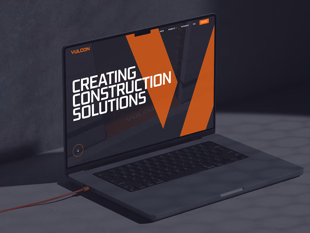 Open laptop showing a webpage with text 'Creating Construction Solutions' and orange design elements.