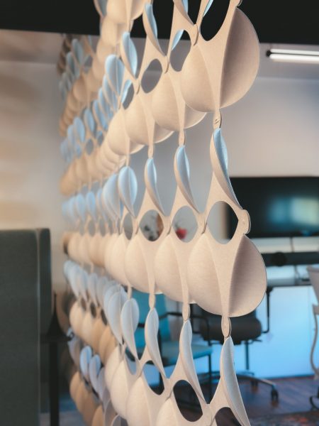 Abstract close-up of hanging beige felt panels with circular cutouts in an office space.