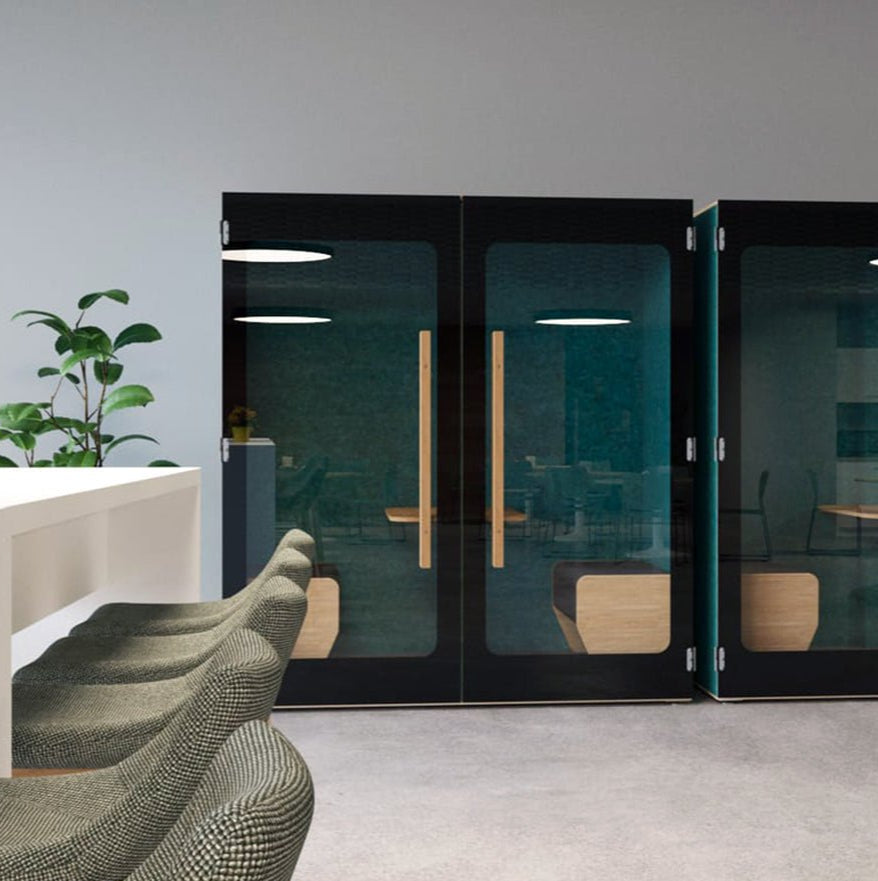 Moderne kantoorruimte met zwarte geluidsdichte telefooncabines en grijze stoelen bij een wit bureau.