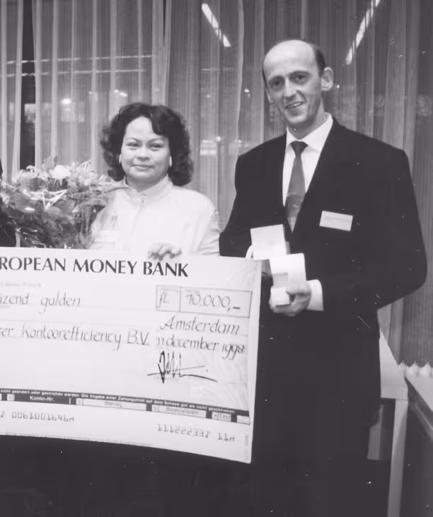 Twee mensen poseren met een grote cheque van 70.000 gulden in Amsterdam, december 1992.