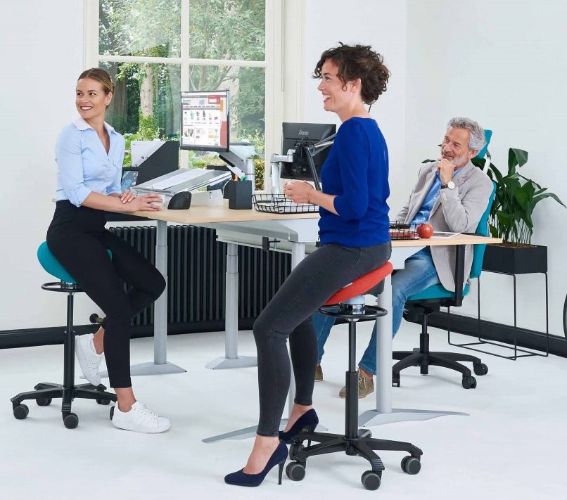 Drie mensen ontspannen op bureaustoelen in een lichte kantoorruimte met computers en planten.