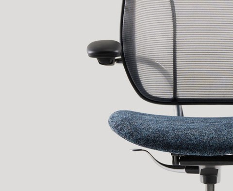 Close-up van een bureaustoel met een zwarte mesh rugleuning, een verstelbare armleuning, en een blauw zittingkussen.